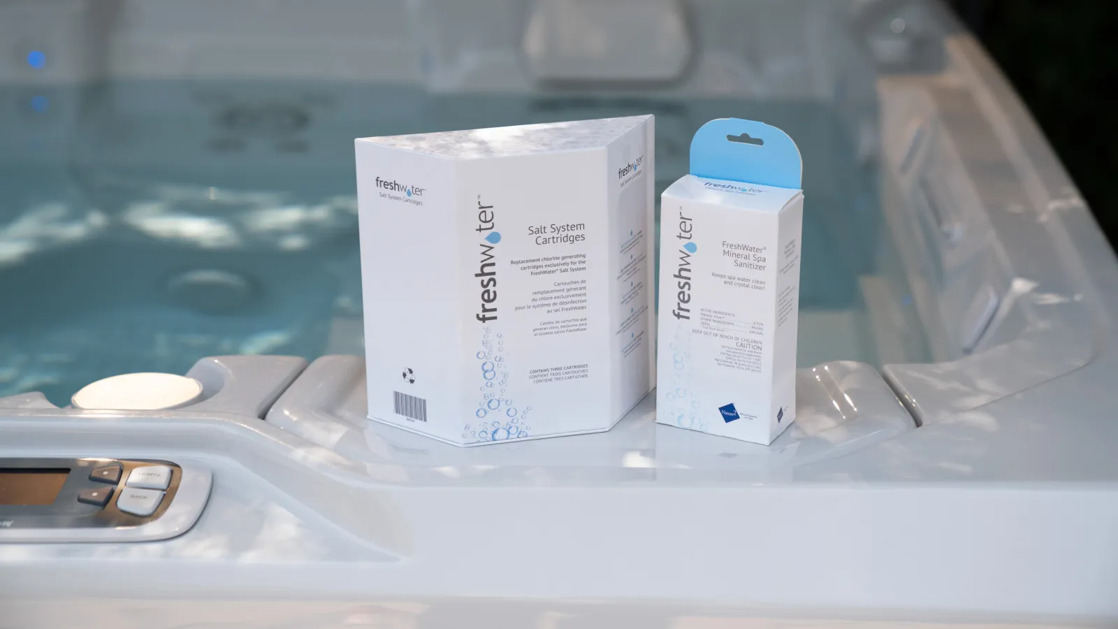 Freshwater salt system and mineral spa salt cartridges displayed on the edge of a white hot tub with water in the background