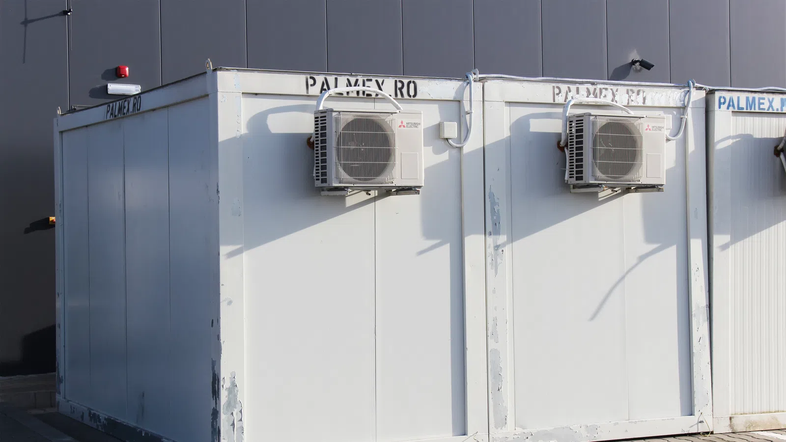 White modular portable buildings with air conditioning units mounted on the side outdoors