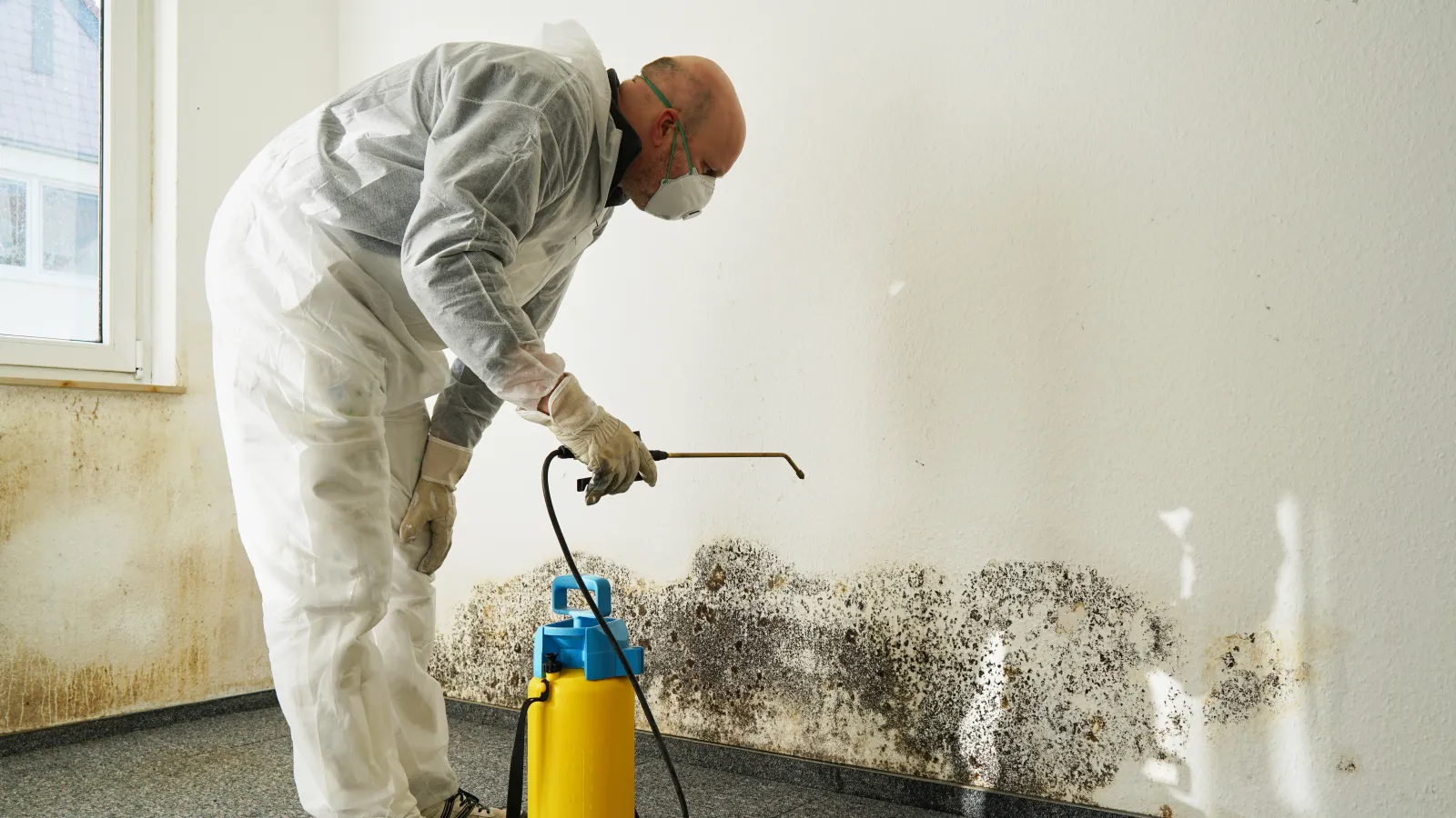 a man in a white lab coat using a hose to water a yellow cylinder