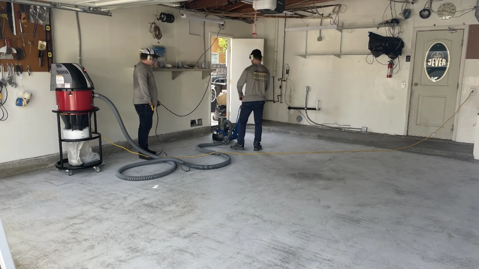 two men in a garage prepping the floor