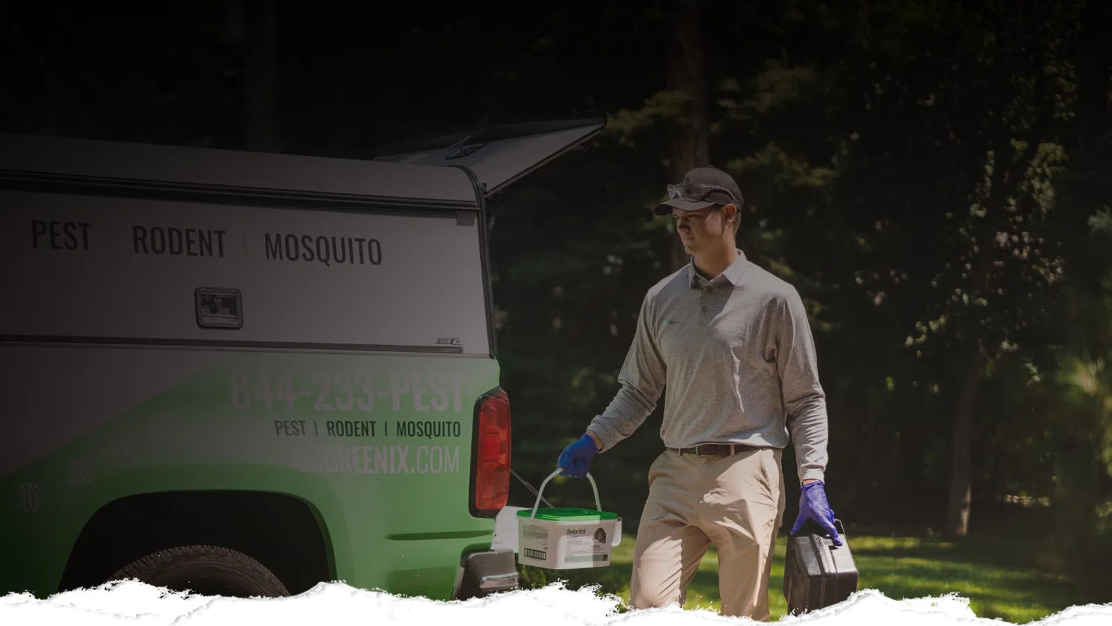 Pest control worker carrying equipment next to a branded truck in a sunny outdoor setting.