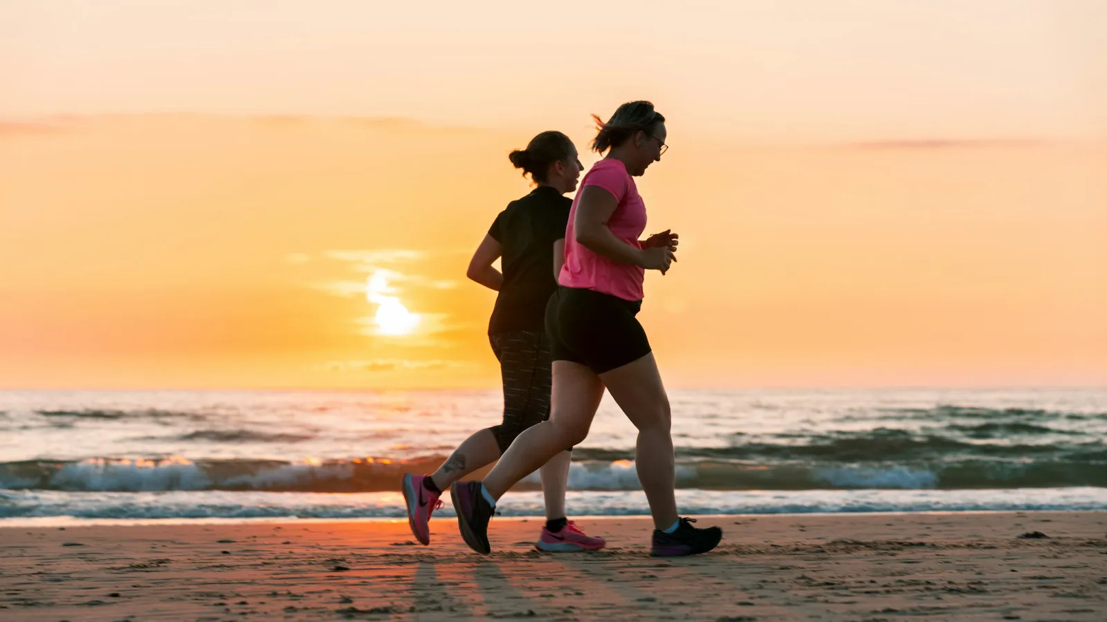 a man and woman running on a beach