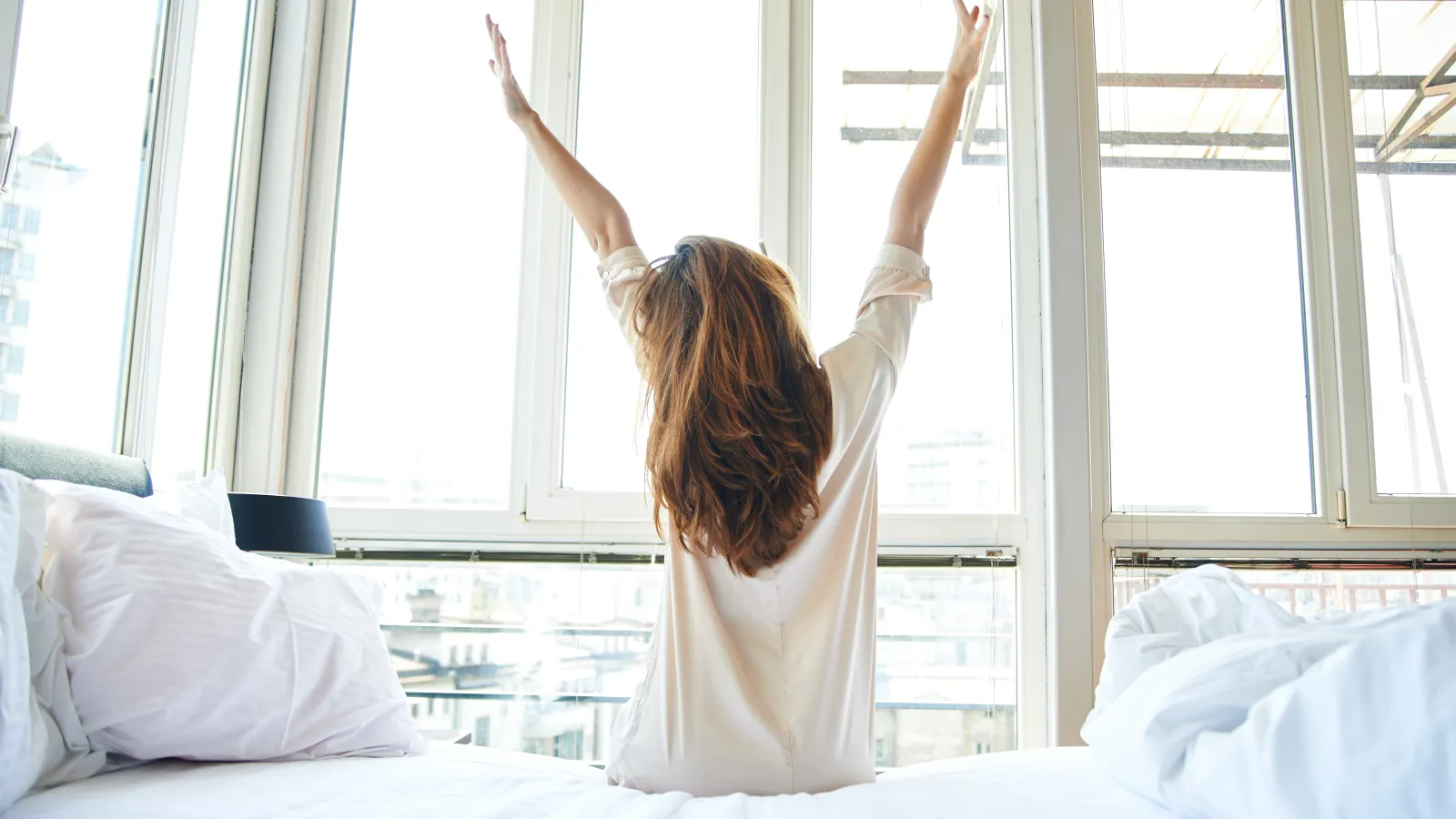 a person raising the arms in the air in front of a window