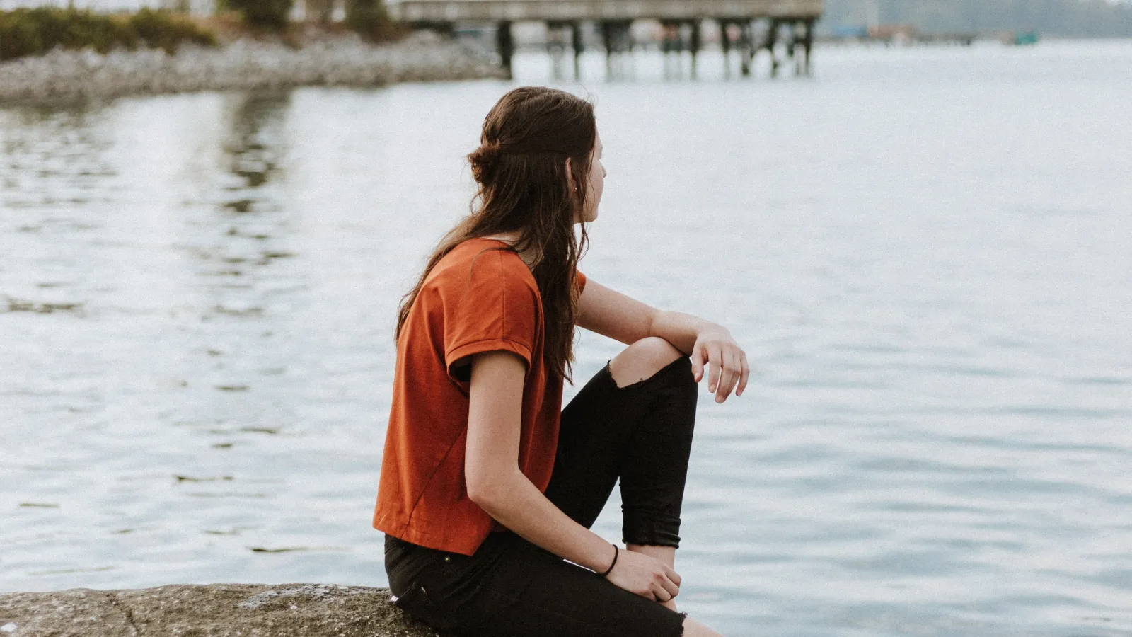 a woman sitting on a rock in the water