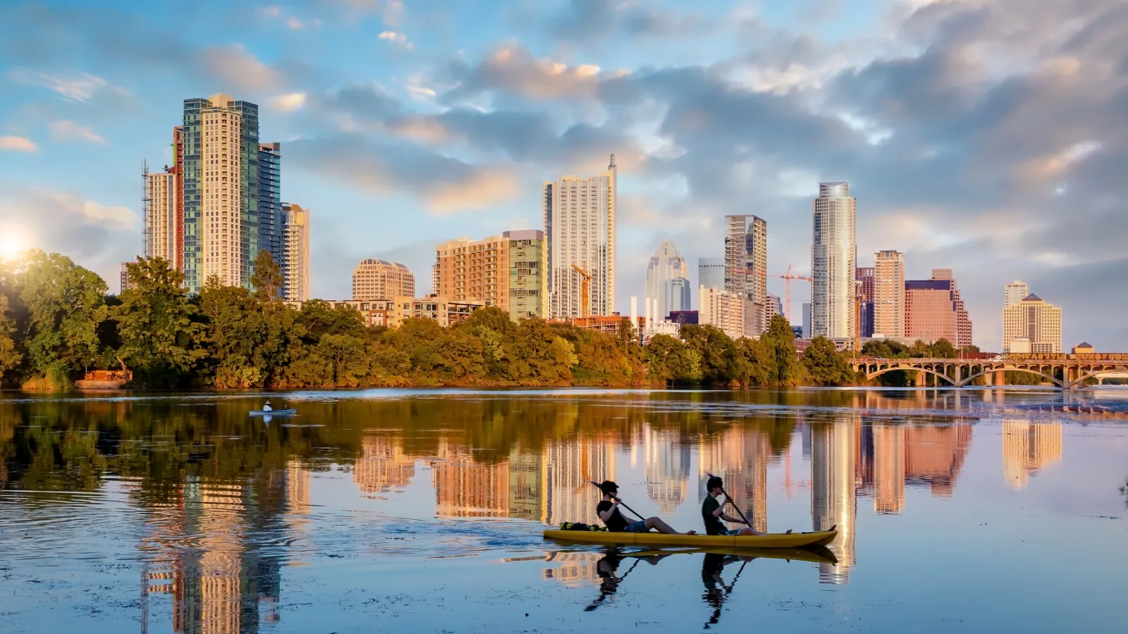 a couple of people on a boat in a lake with a city in the background