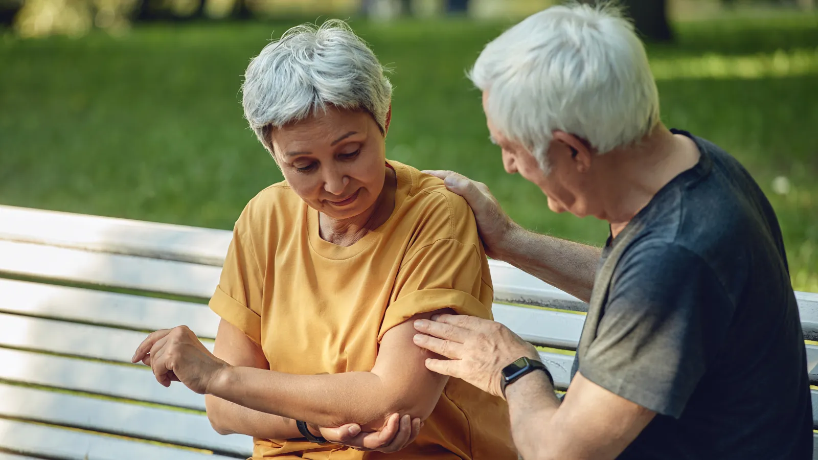 an older man and woman sitting on a bench