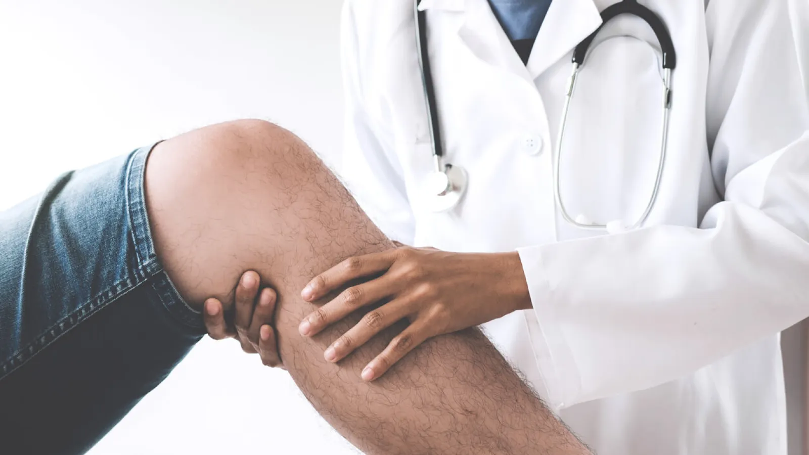 An orthopedic doctor examining a patient's knee in a clinical setting, highlighting medical care and attention.