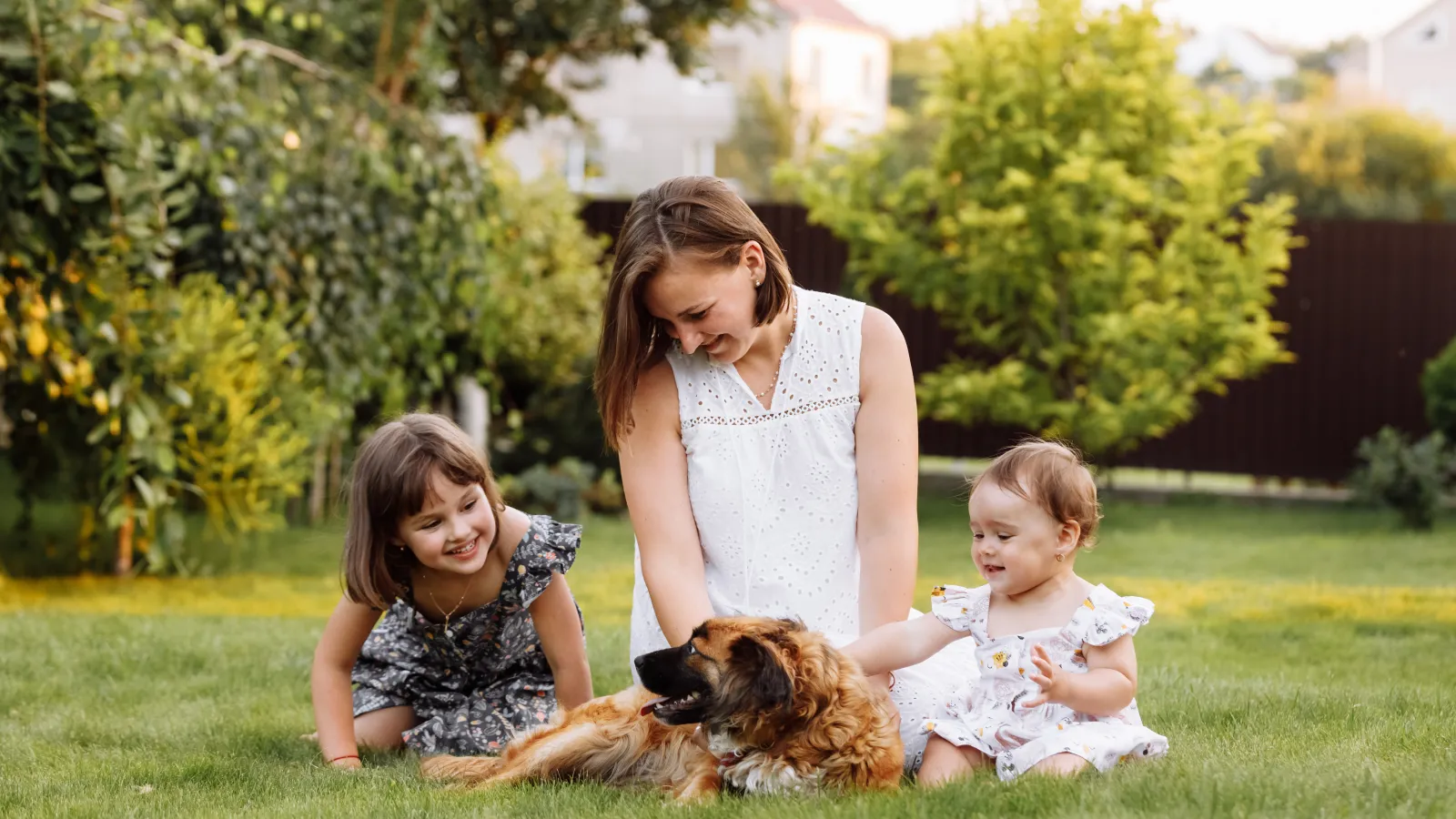 a woman and two children sitting in the grass with a dog