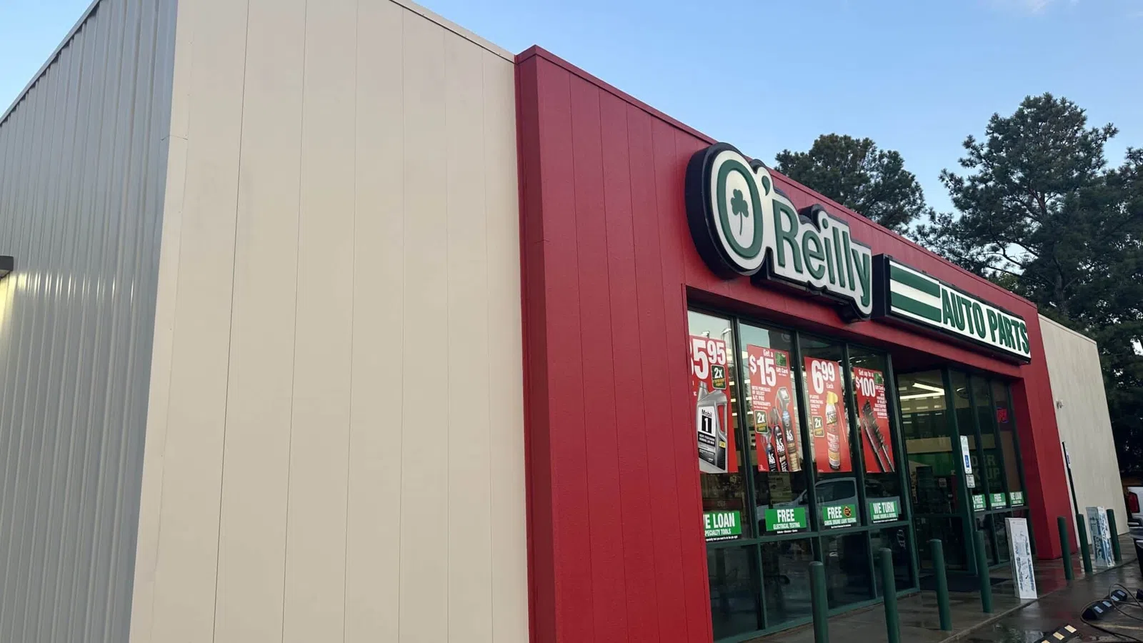Exterior view of O'Reilly Auto Parts store with red and white facade and promotional posters on windows.