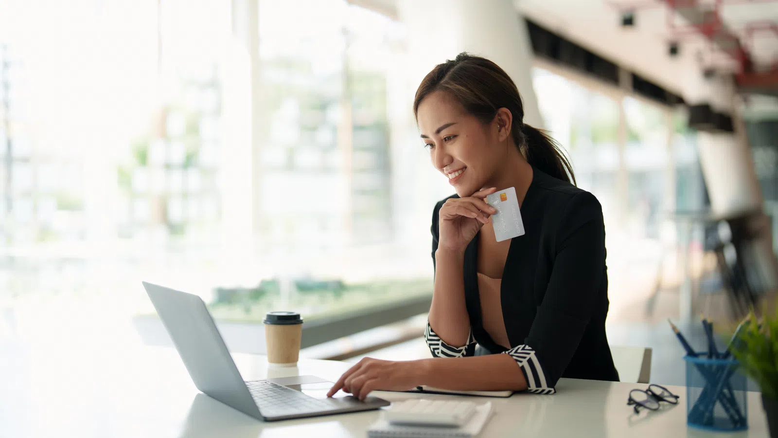 a woman sitting at a table with a laptop and a phone