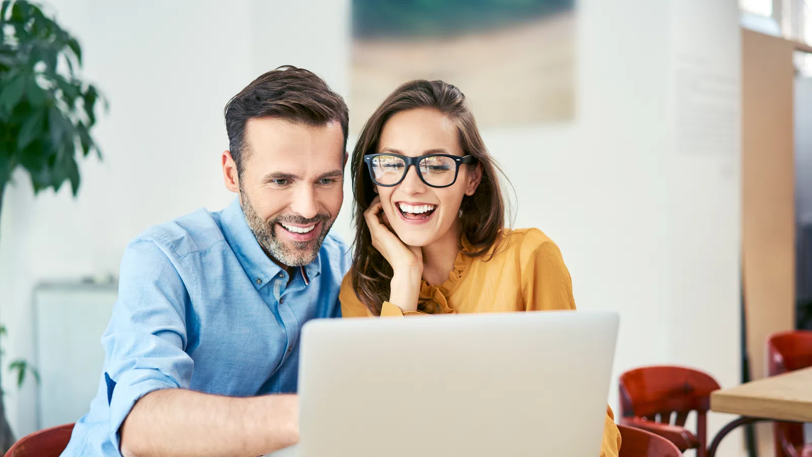 a man and a woman smiling at a laptop
