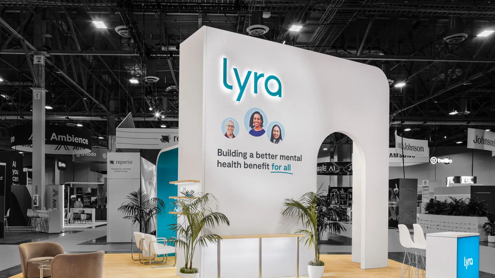 Modern Lyra mental health booth with clean design, light wood flooring, plants, and comfortable seating in expo hall