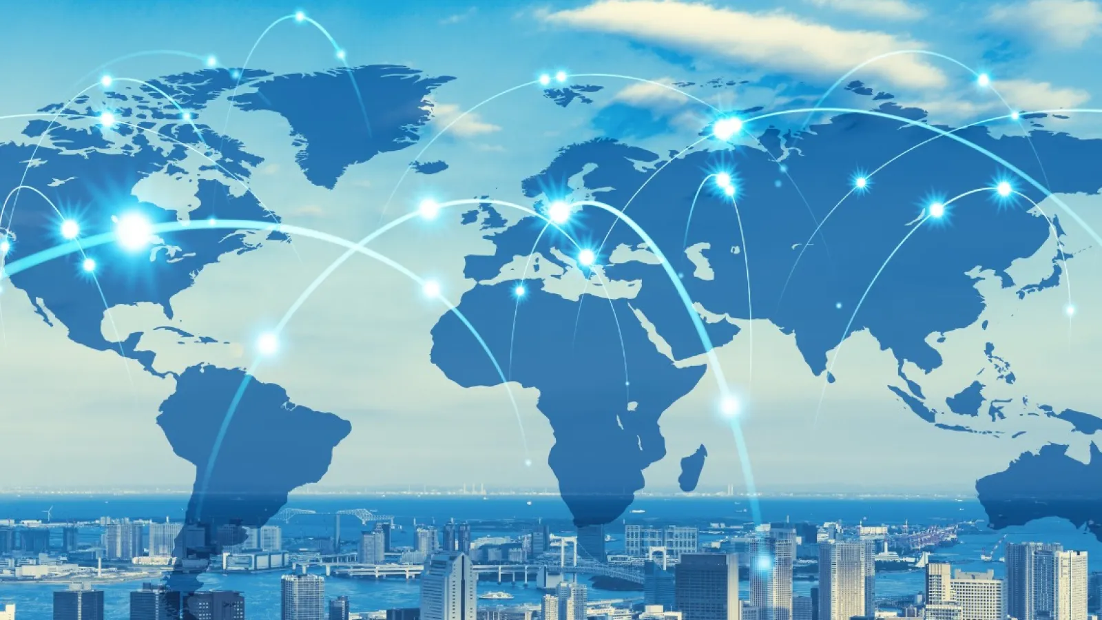 Global digital network connections overlay on cityscape under blue sky representing worldwide communication.