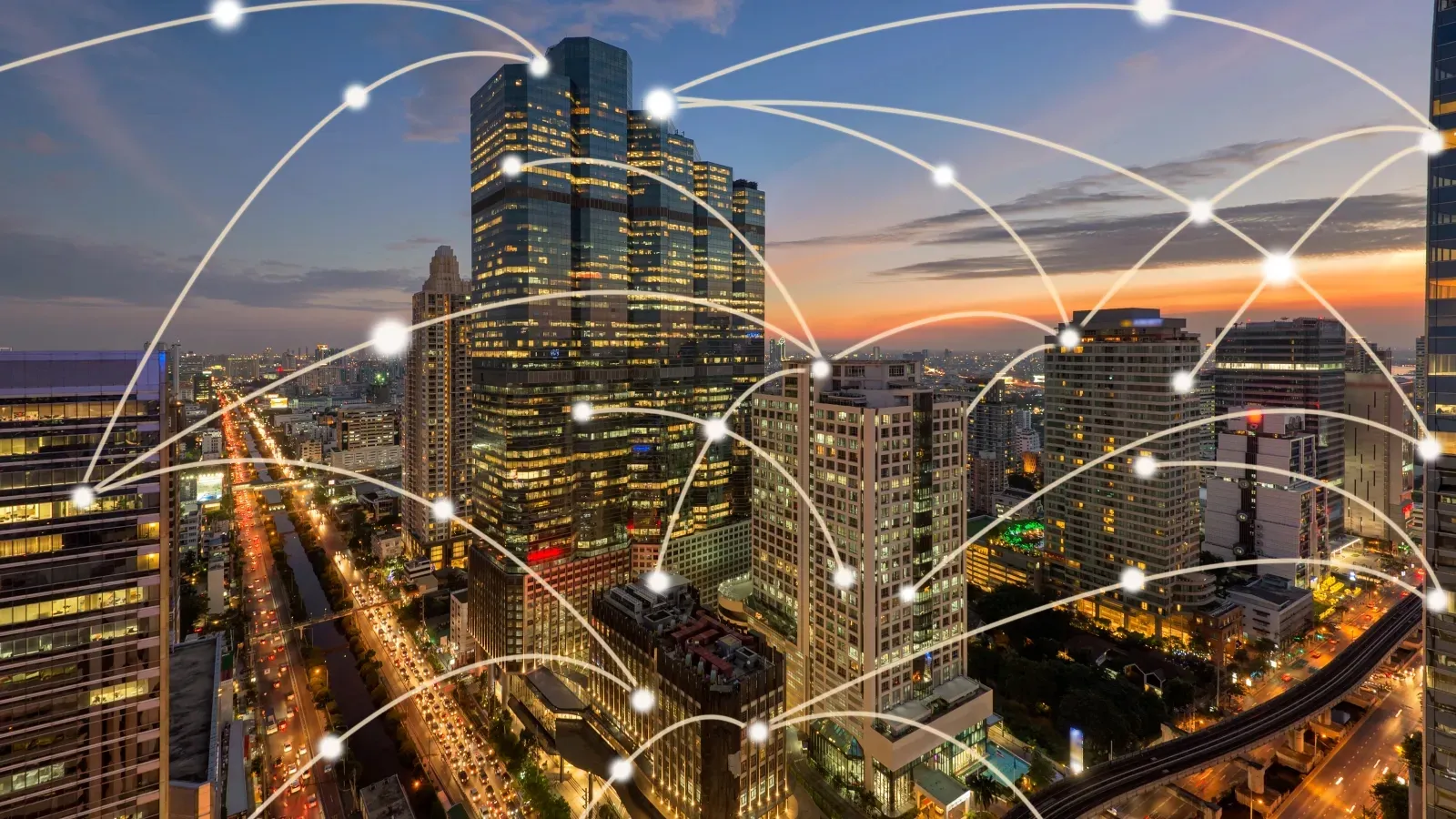City skyline at dusk with skyscrapers connected by glowing digital network lines symbolizing global communication.