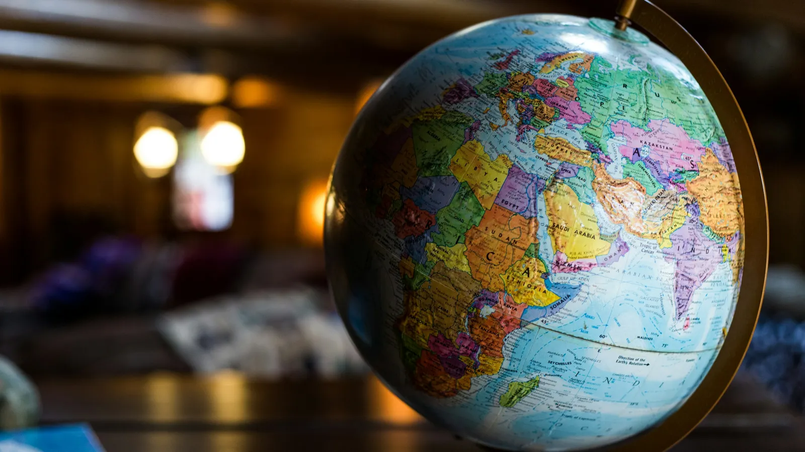 Close-up of a colorful globe showing Africa, Europe, and Asia on a wooden table with blurred background.