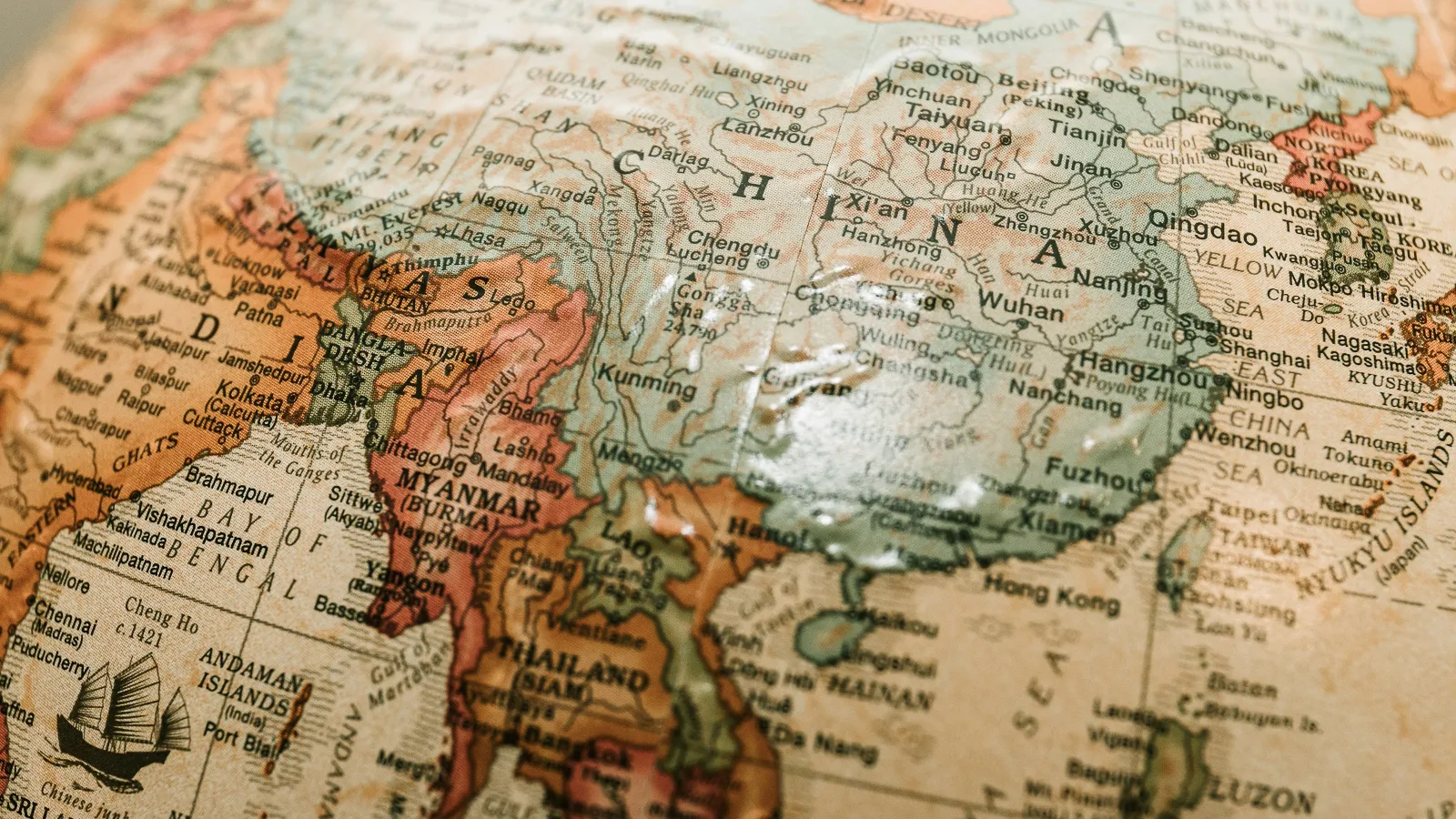 Close-up of a vintage globe showing countries in Asia, including China, Myanmar, Thailand, and India.