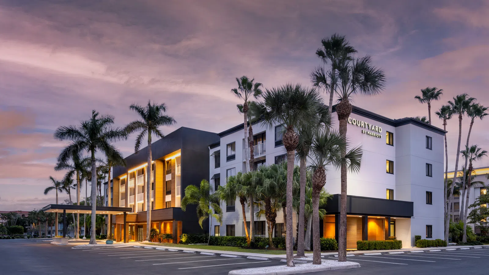 Modern Courtyard by Marriott hotel building with palm trees at sunset and empty parking lot