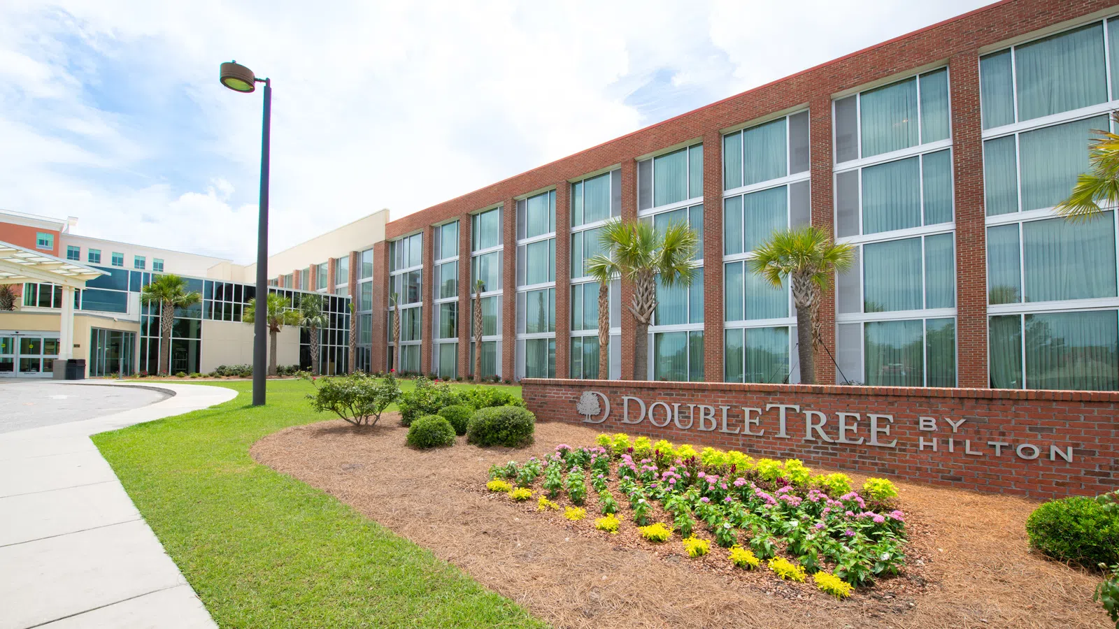 DoubleTree by Hilton hotel building with palm trees and clear blue sky during daytime.