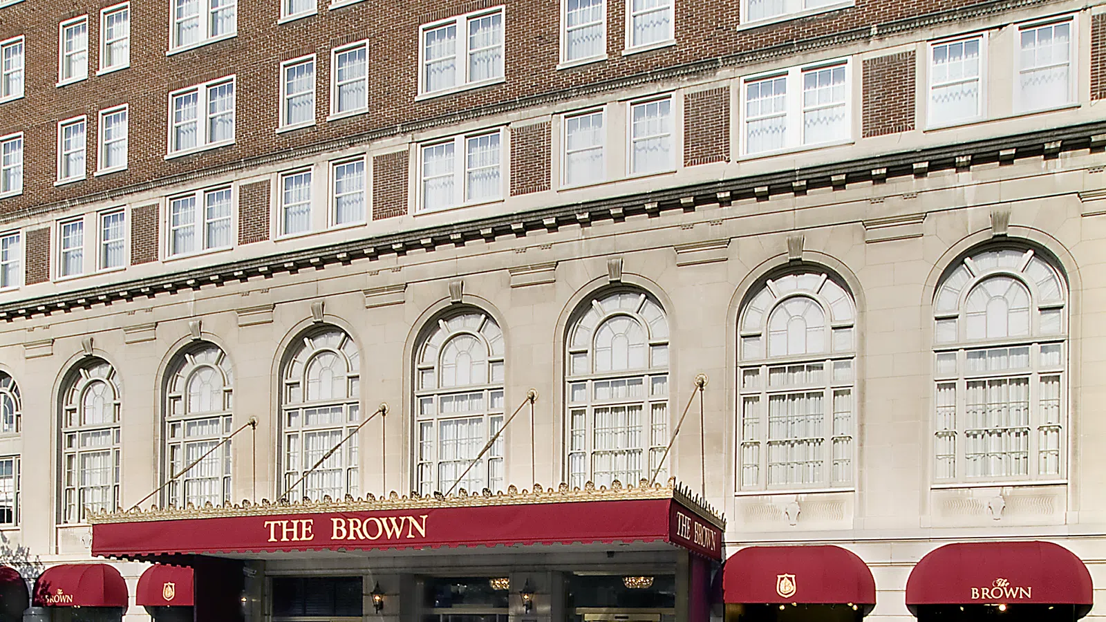 Historic The Brown Hotel entrance with red awnings and classic architecture under bright daylight