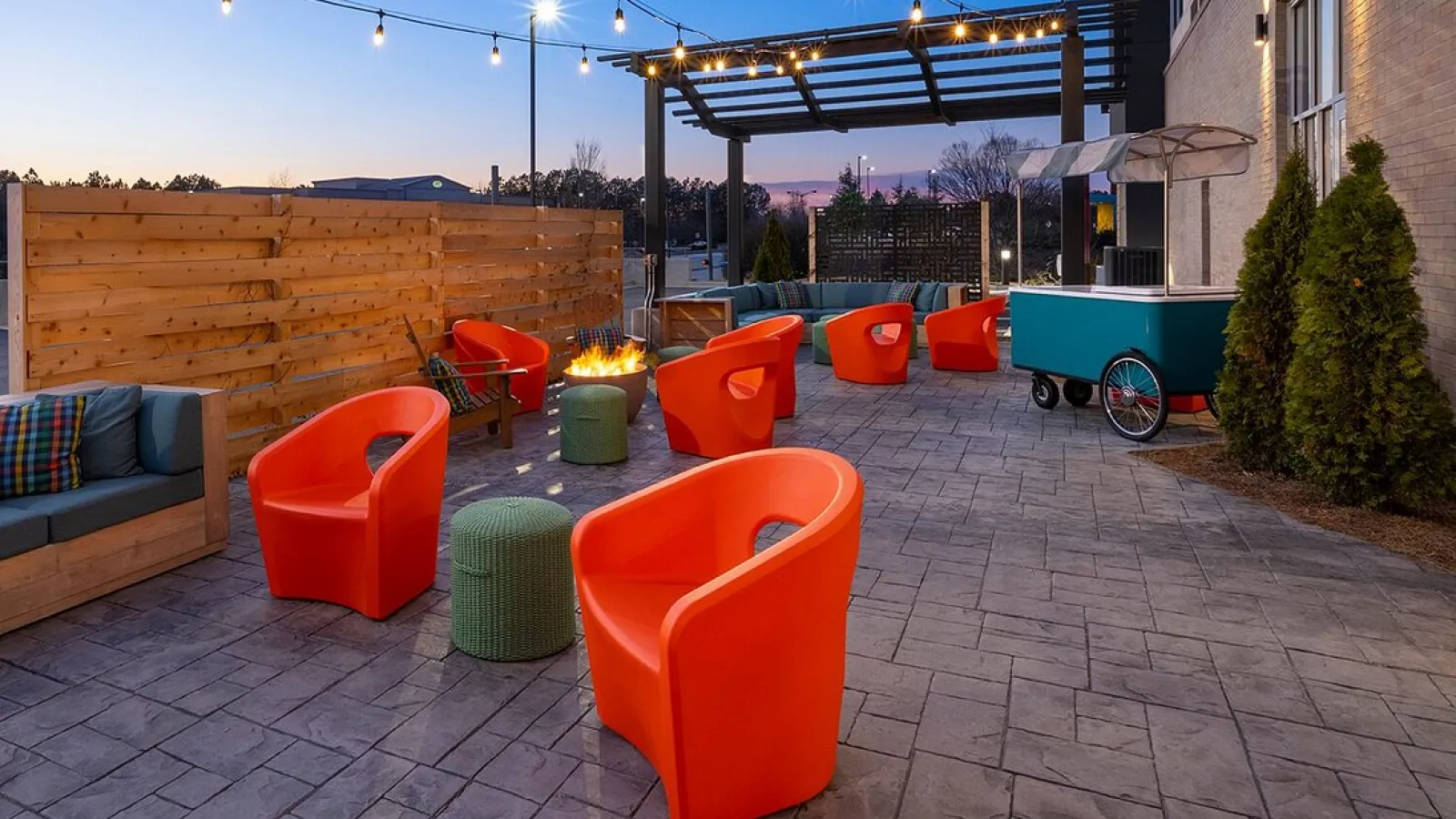 a patio with orange chairs and a wood fence with a wood wall and a blue sky