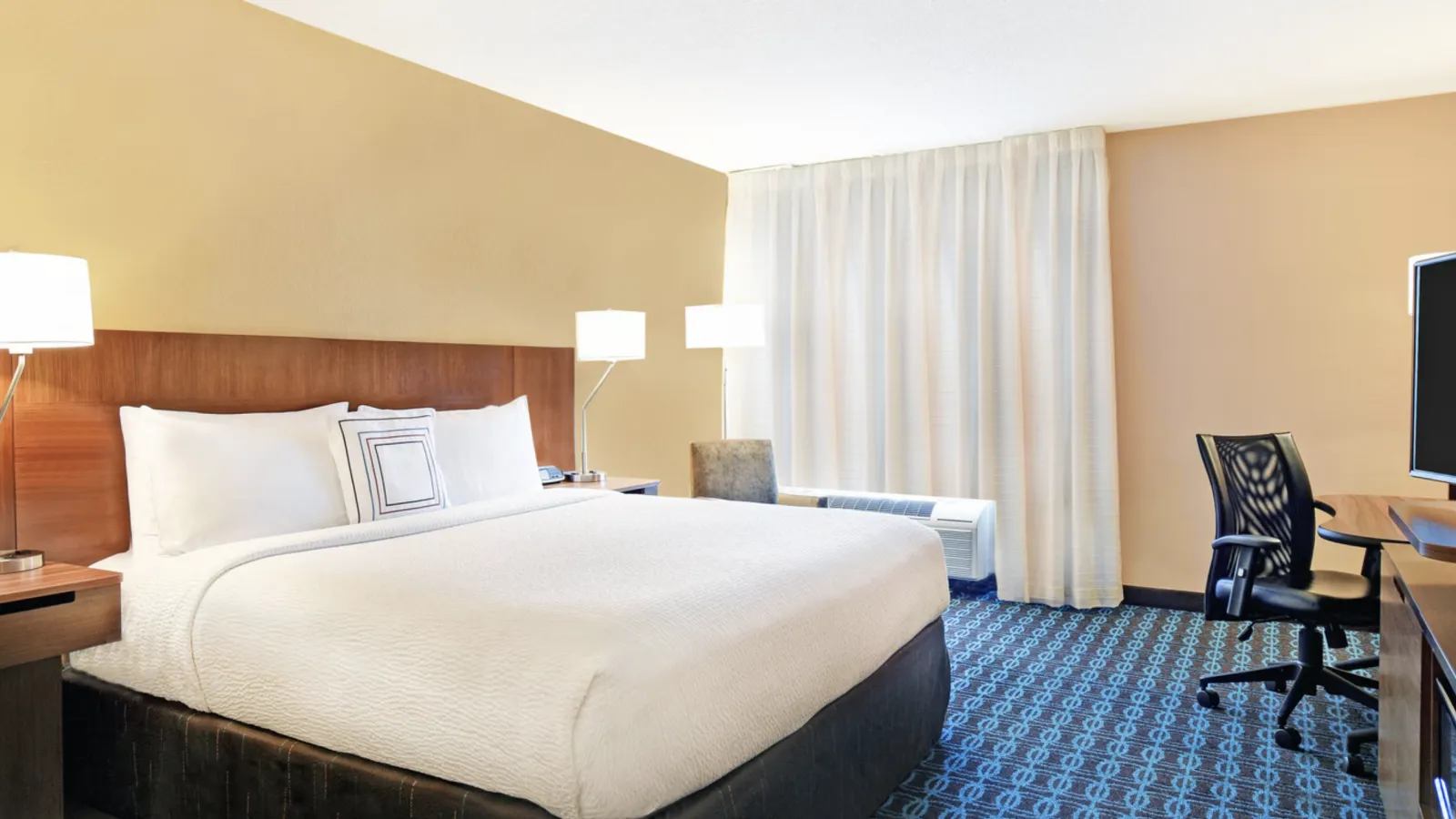 a hotel room with a bed and desk