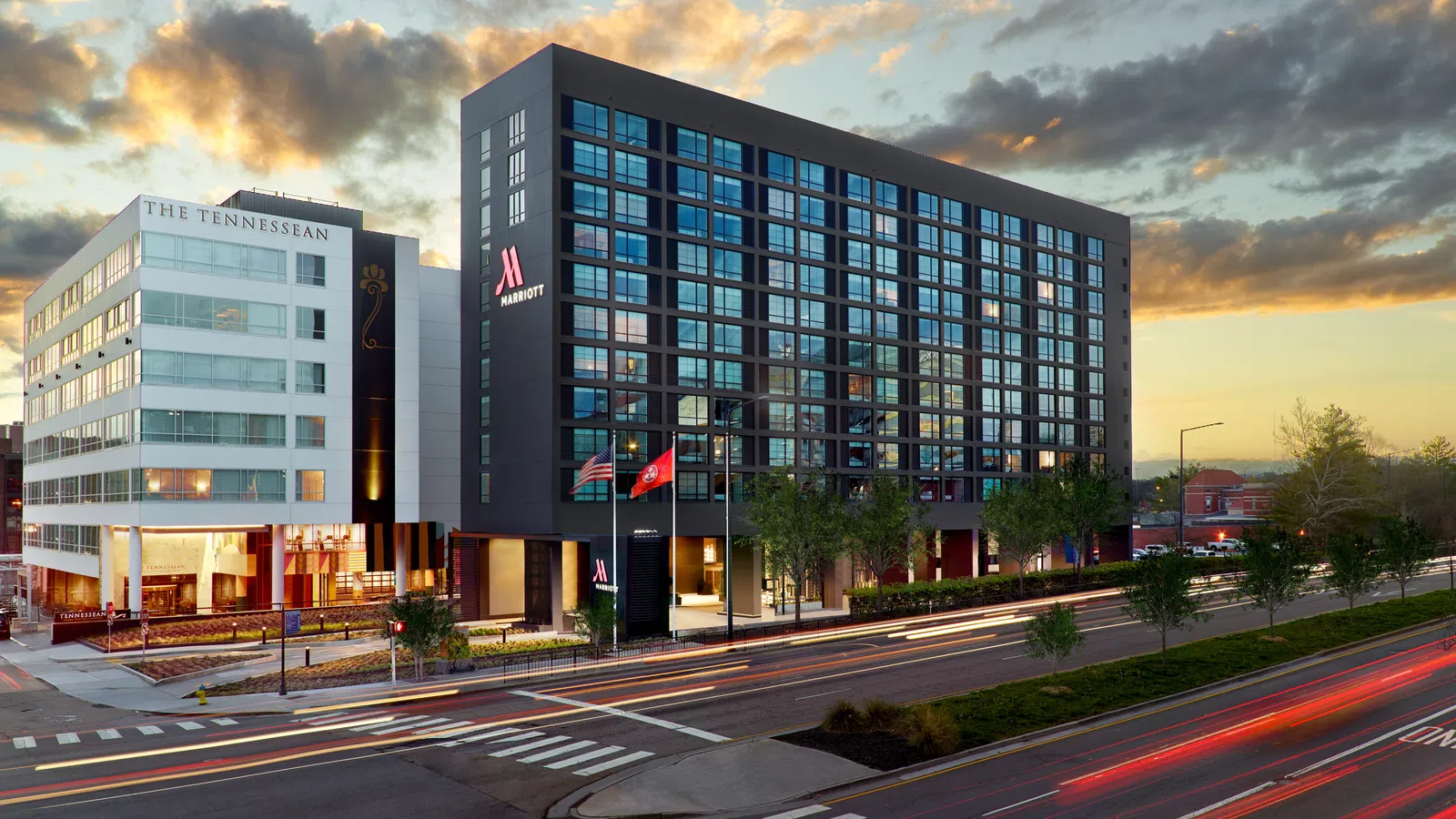 Marriott hotel and The Tennessean building at dusk with light trails from passing cars on city street.