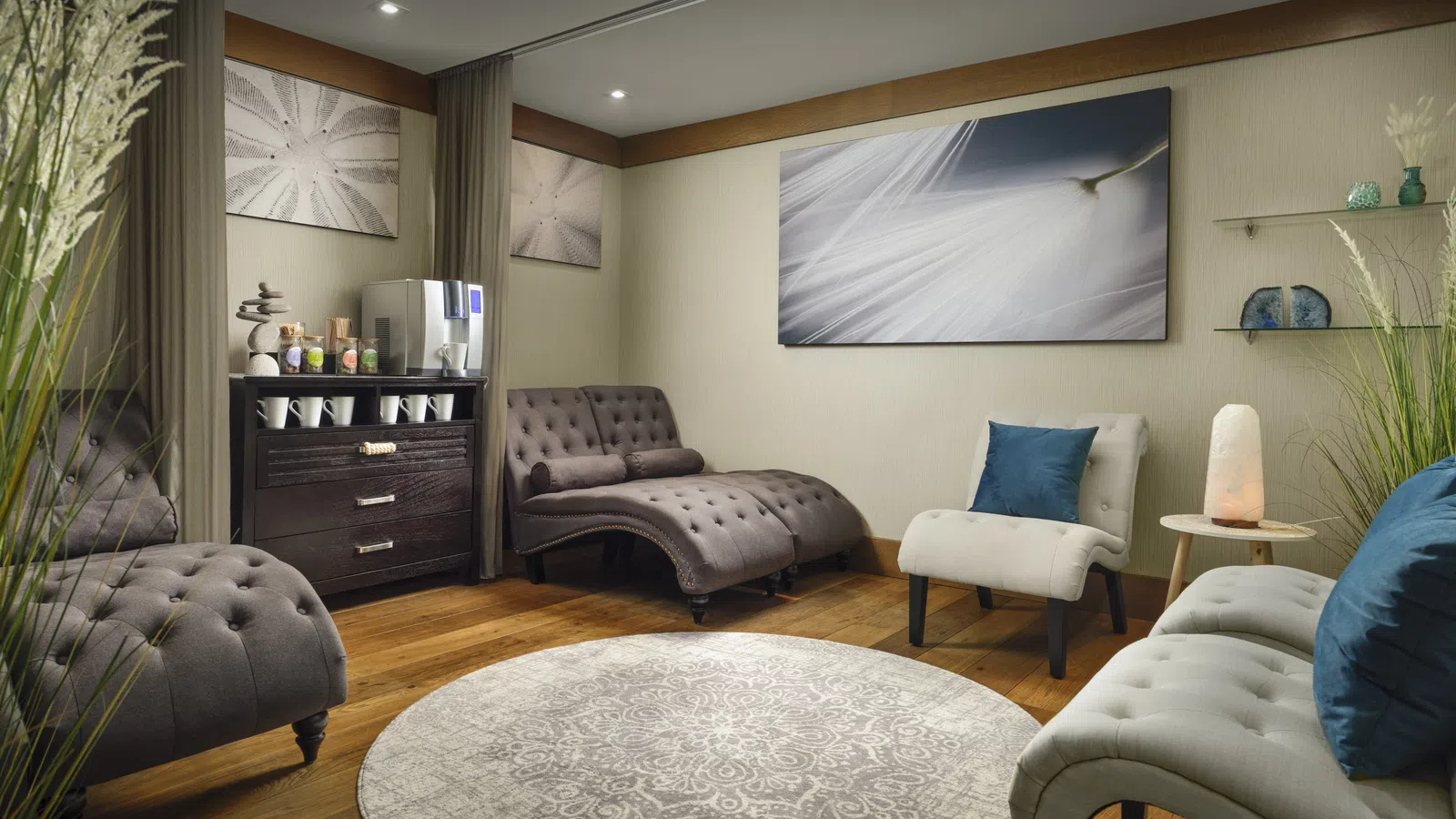 Cozy modern living room with tufted sofas, a round patterned rug, soft lighting, and abstract wall art.