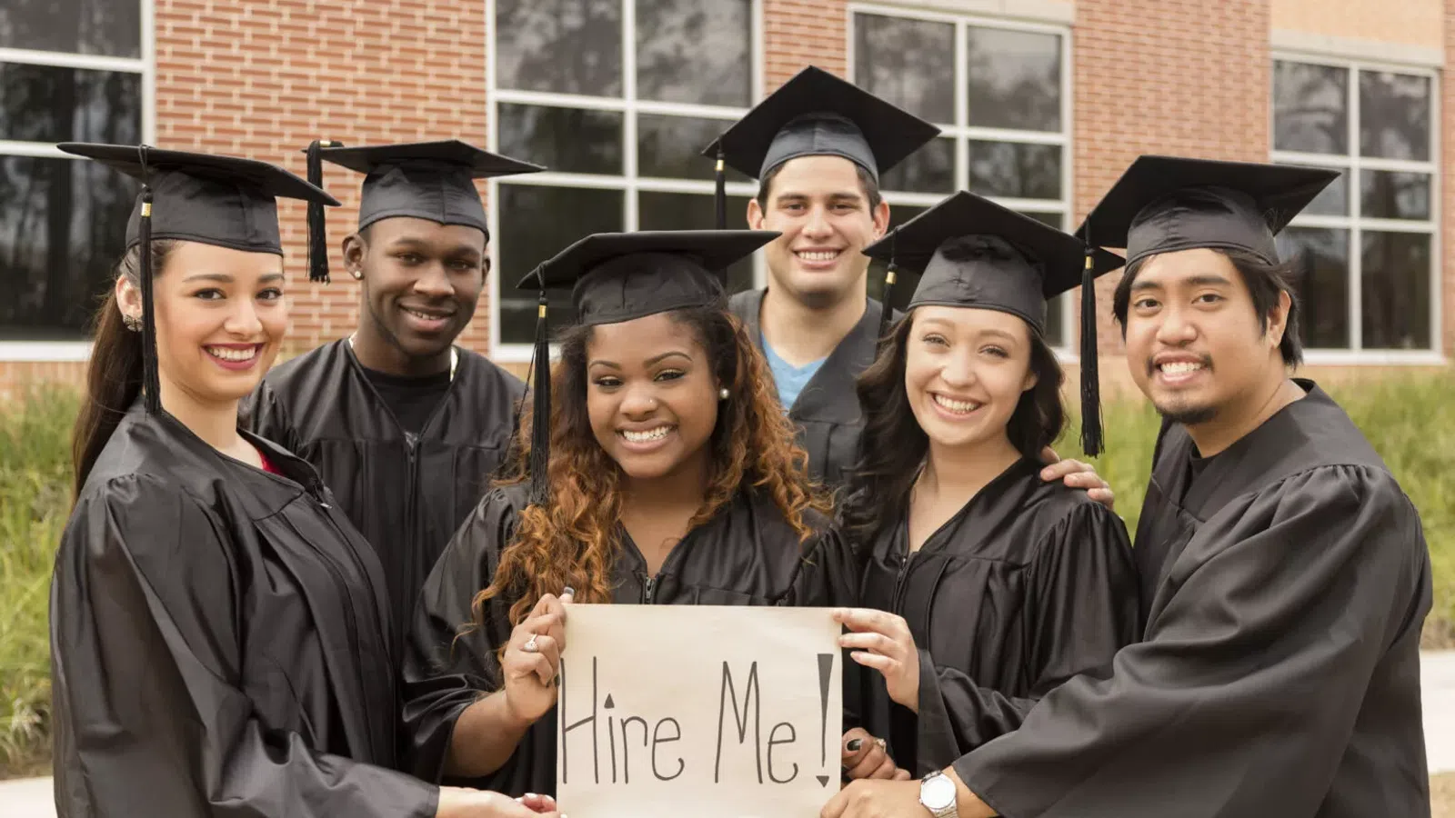 a group of people wearing graduation caps and holding a sign