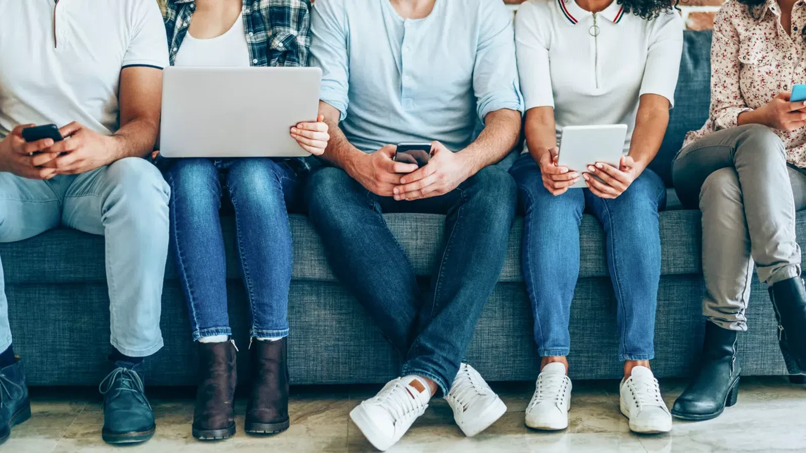 a group of people sitting on a couch looking at their phones