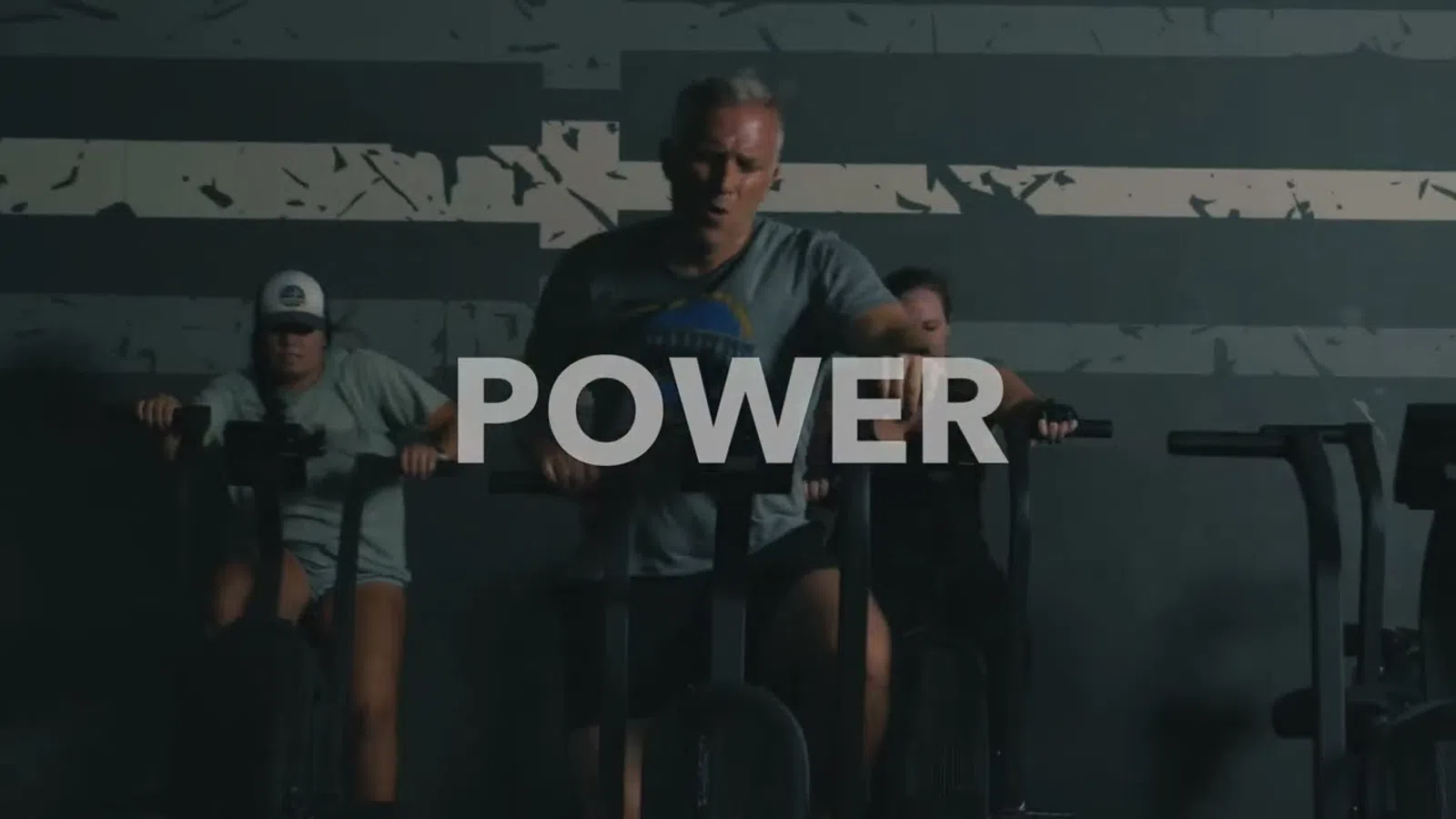 Three people exercising intensely on stationary bikes in a gym with POWER text overlay.