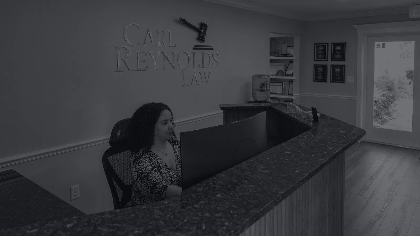 Reception area of Carl Reynolds Law with receptionist at desk and visible office entrance and decor.