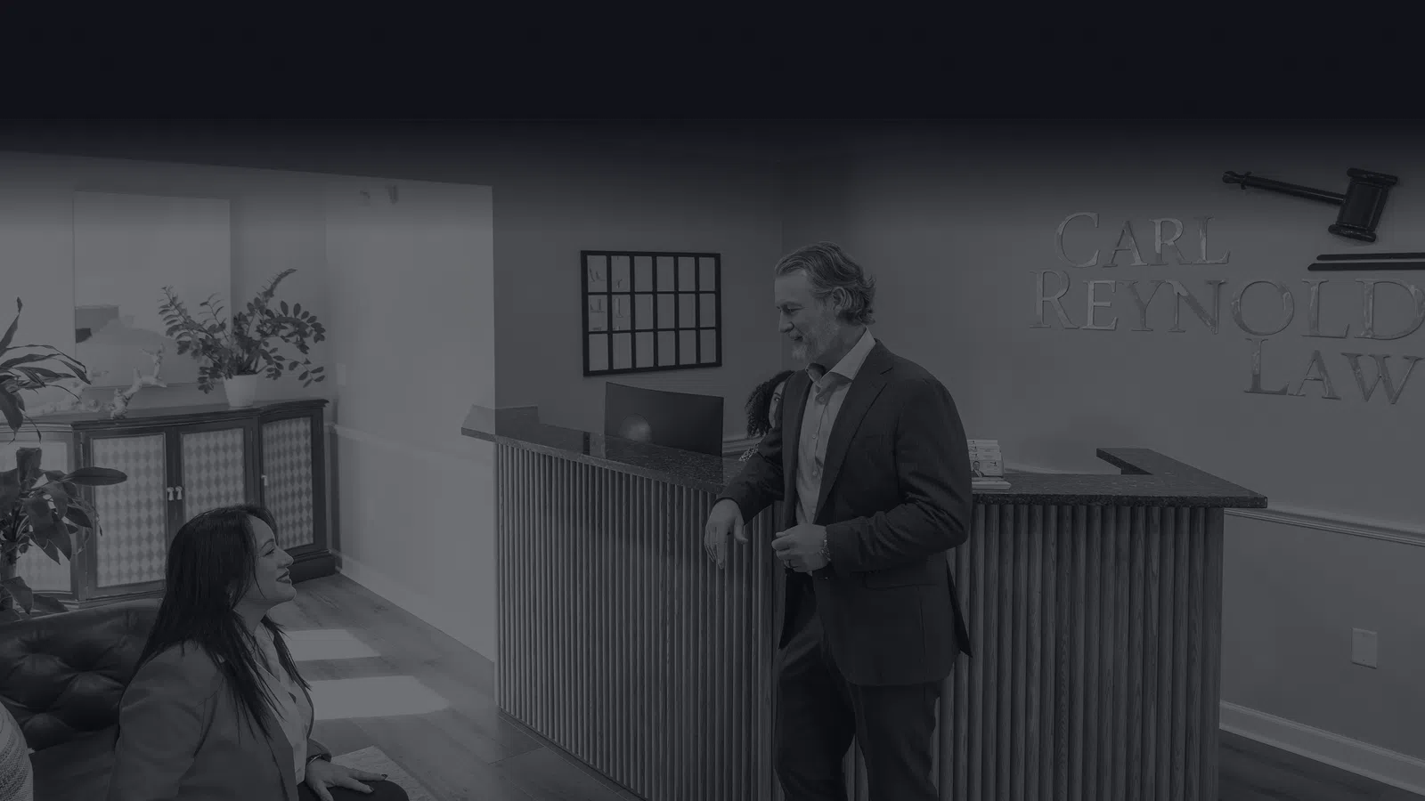 Professional lawyer consulting a client in a modern law office reception area with wooden floors and plants