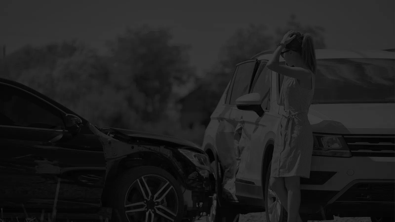 Woman standing beside two damaged cars after a collision on a sunny day in an outdoor setting.