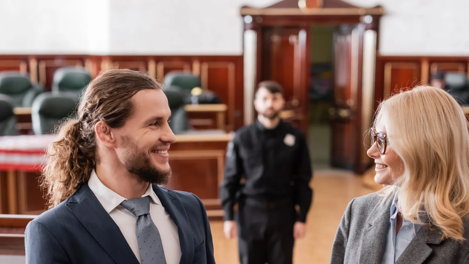 Happy lawyer celebrating a courtroom victory while discussing with a female colleague holding a notebook