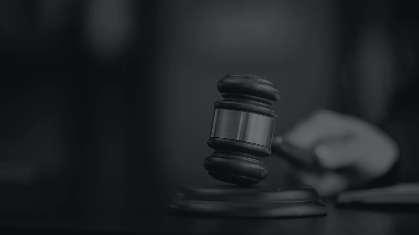 Judge's wooden gavel striking sounding block symbolizing justice and law in courtroom setting.