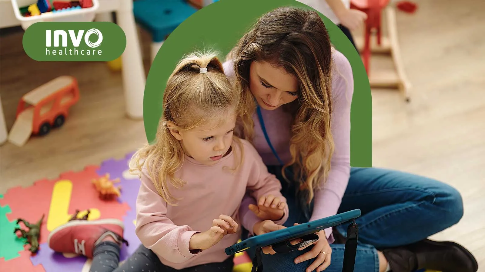 A caregiver and child engaged with a tablet in a colorful playroom setting.