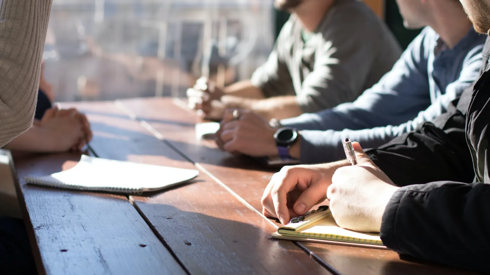 a group of people sitting at a table writing on paper