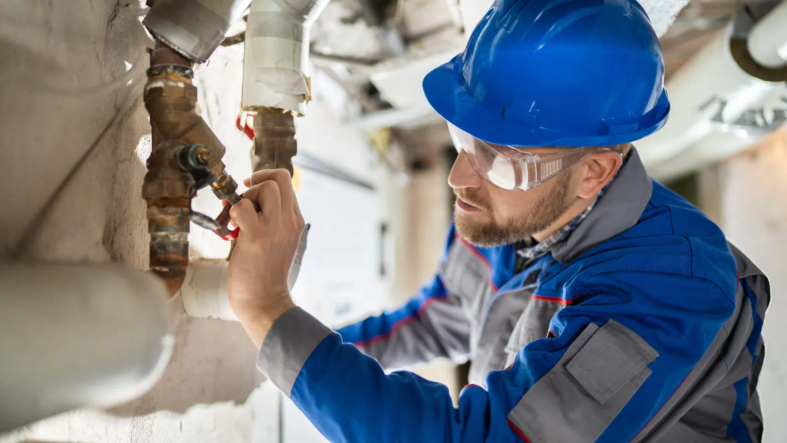 a man wearing a hard hat and protective gear working on a pipe