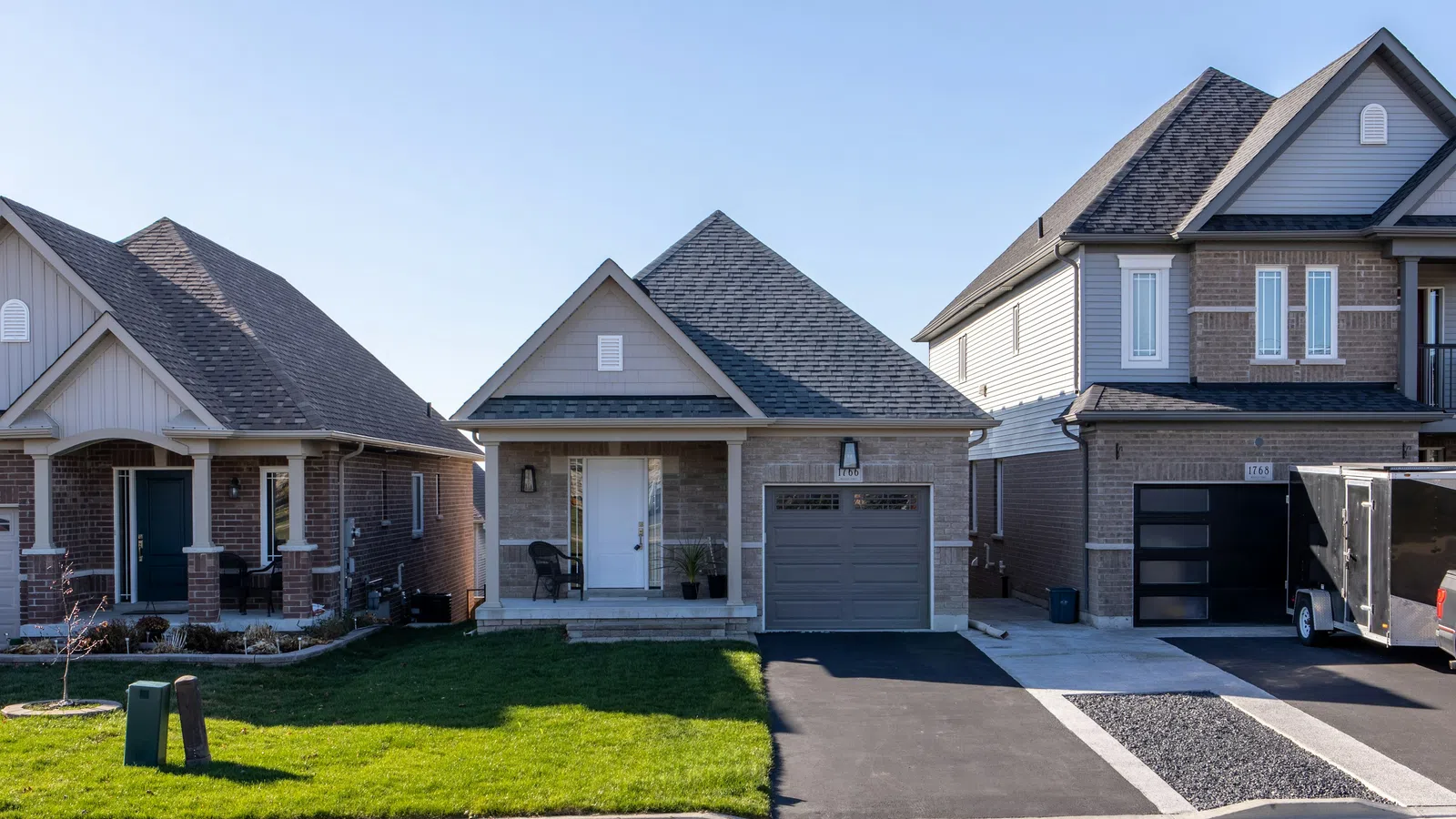 Suburban neighborhood with single-family homes featuring porches, garages, and well-maintained lawns on a clear day
