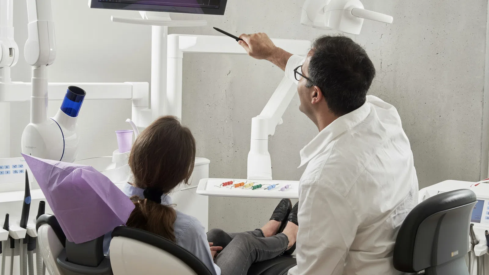 Dentist explaining dental X-ray results to patient in a modern dental clinic setting.