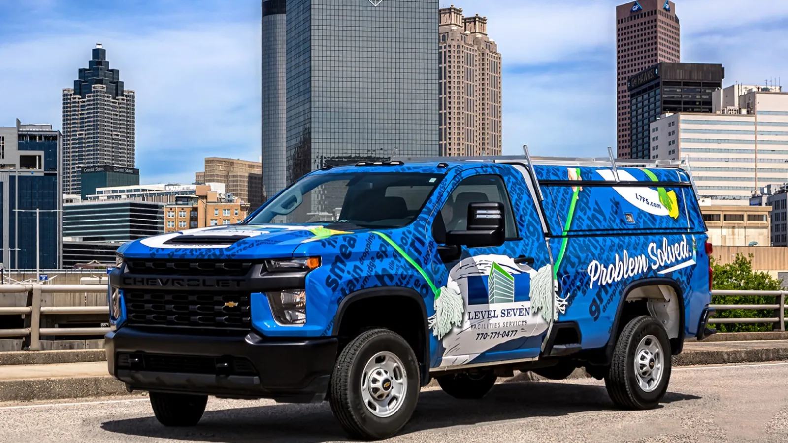 Blue Level Seven service truck parked in front of Atlanta city skyline on a sunny day.