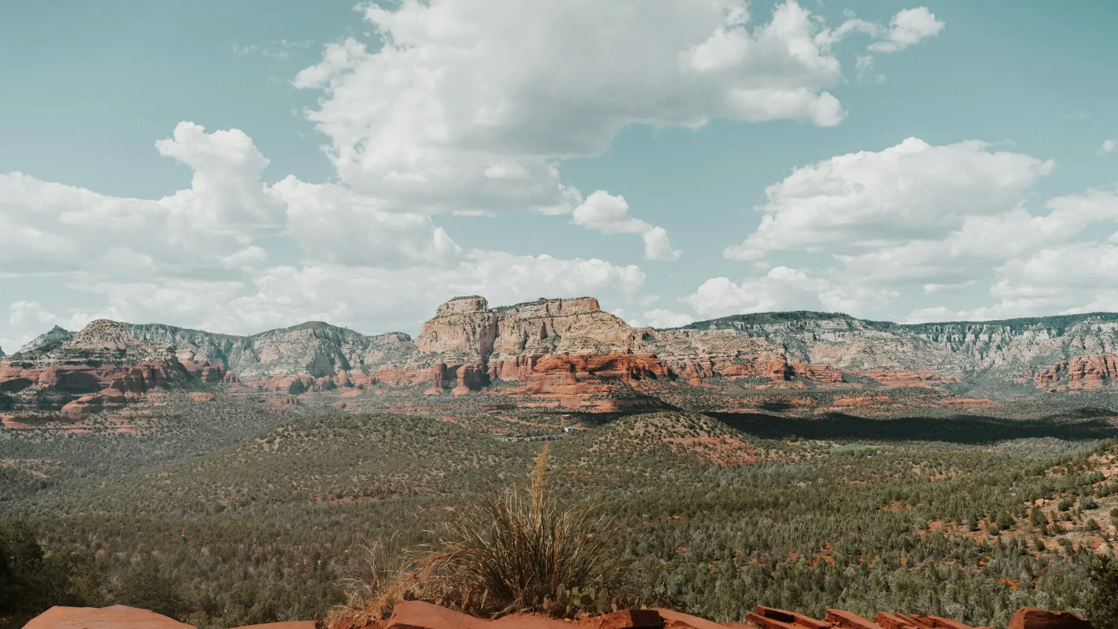 Panoramic view of red rock formations under a blue sky with scattered clouds in a desert landscape