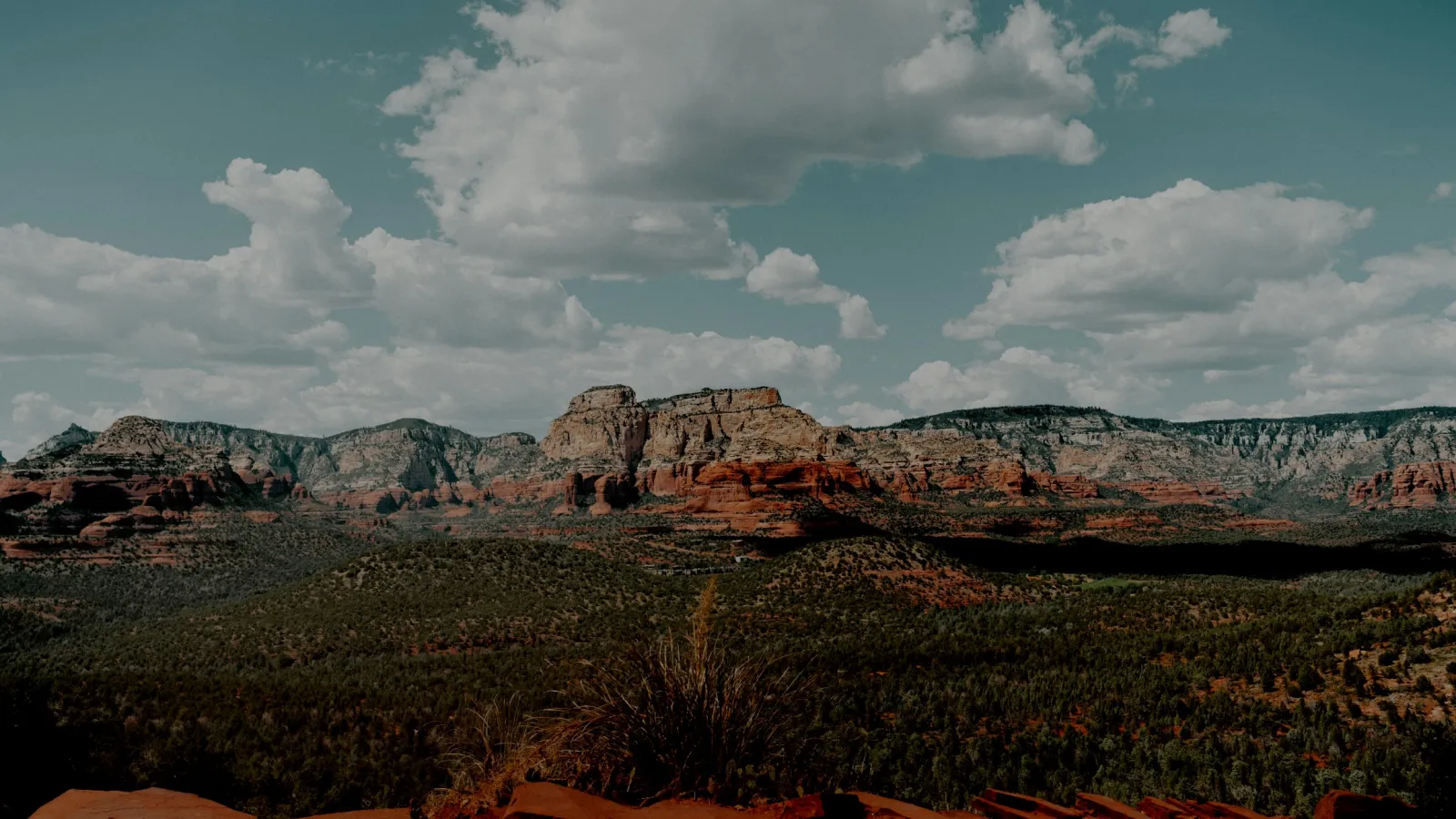 Panoramic view of red rock formations under a blue sky with scattered clouds in a desert landscape