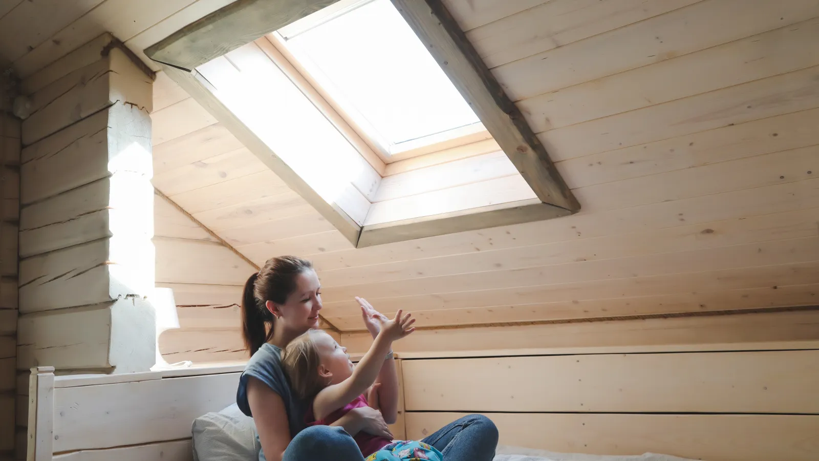 a person and a child sitting on a bed in a wooden cabin