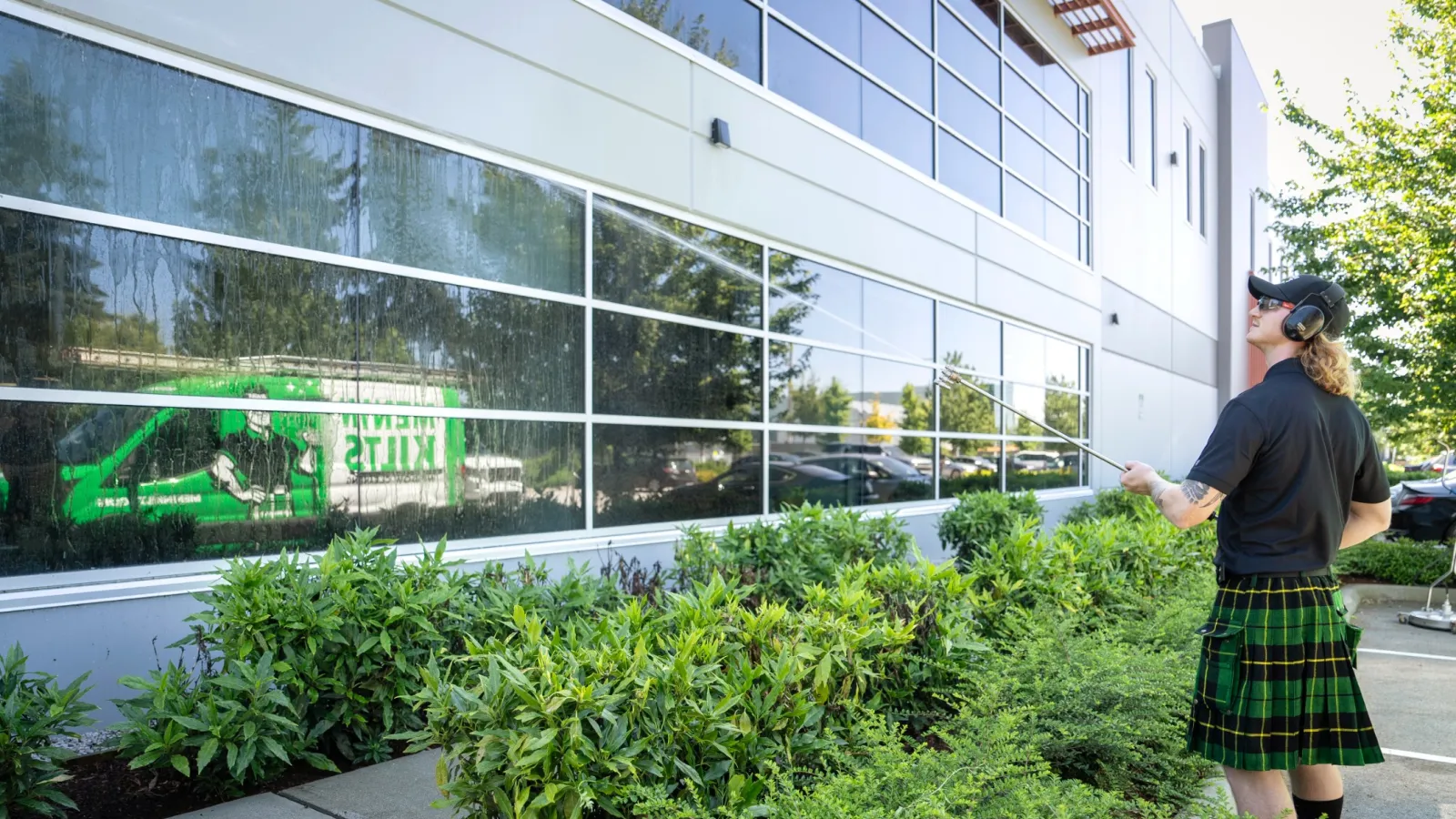 a person standing next to a bush washing a building