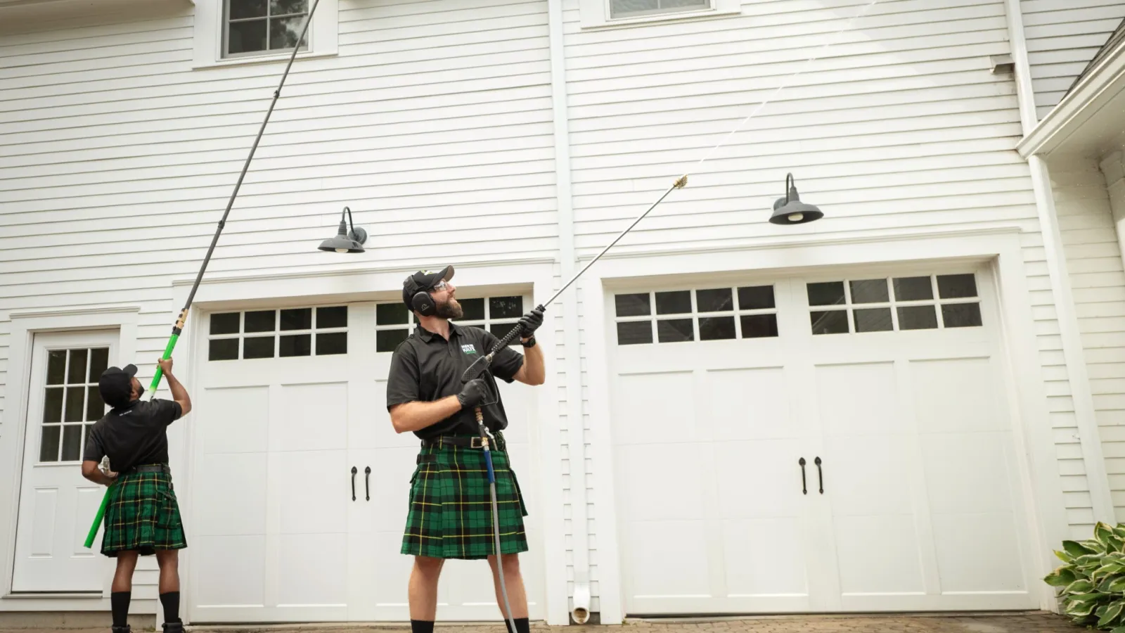 a person in a kilt soft washing a house