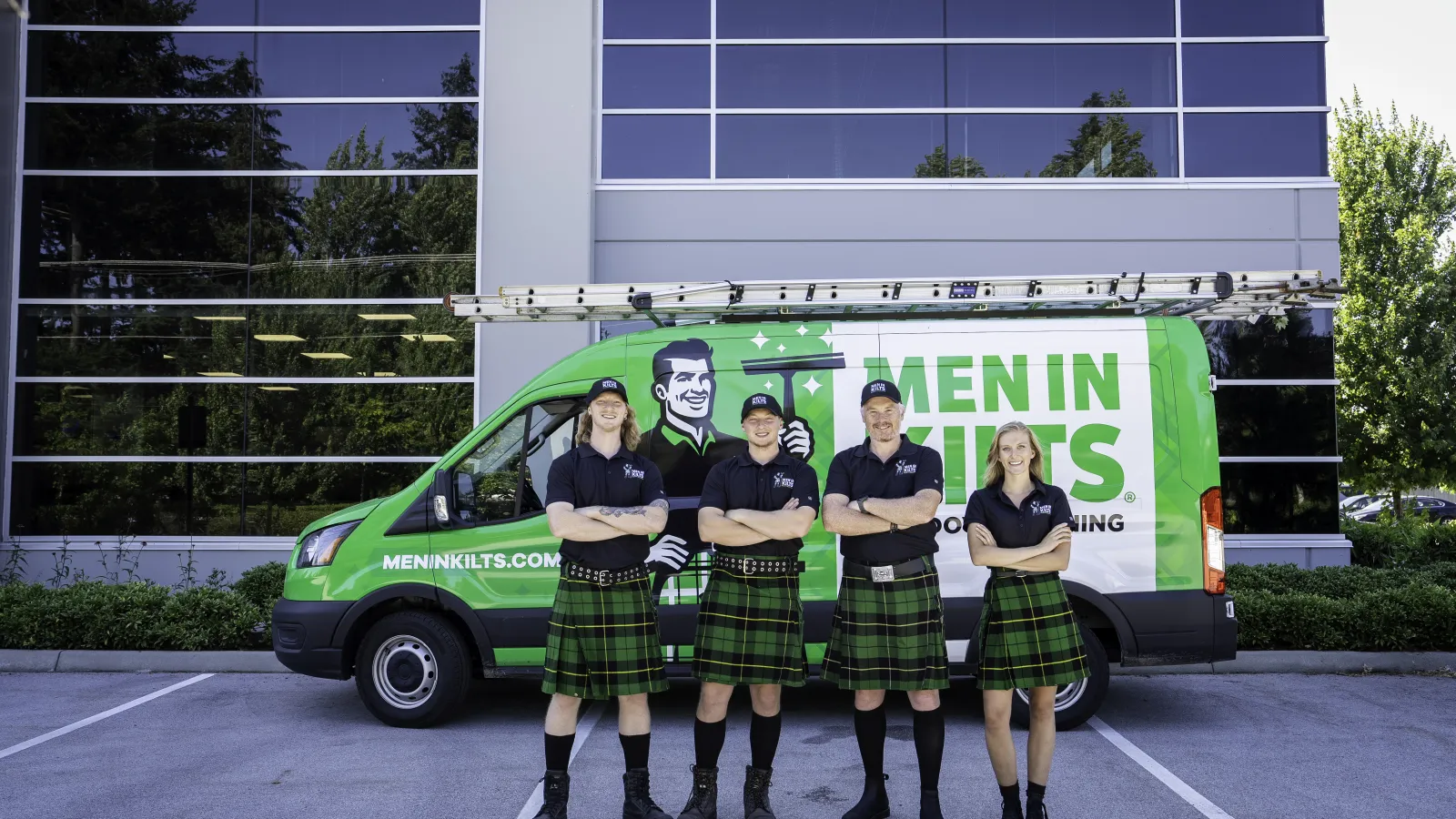 a group of women in kilts standing in front of a green car