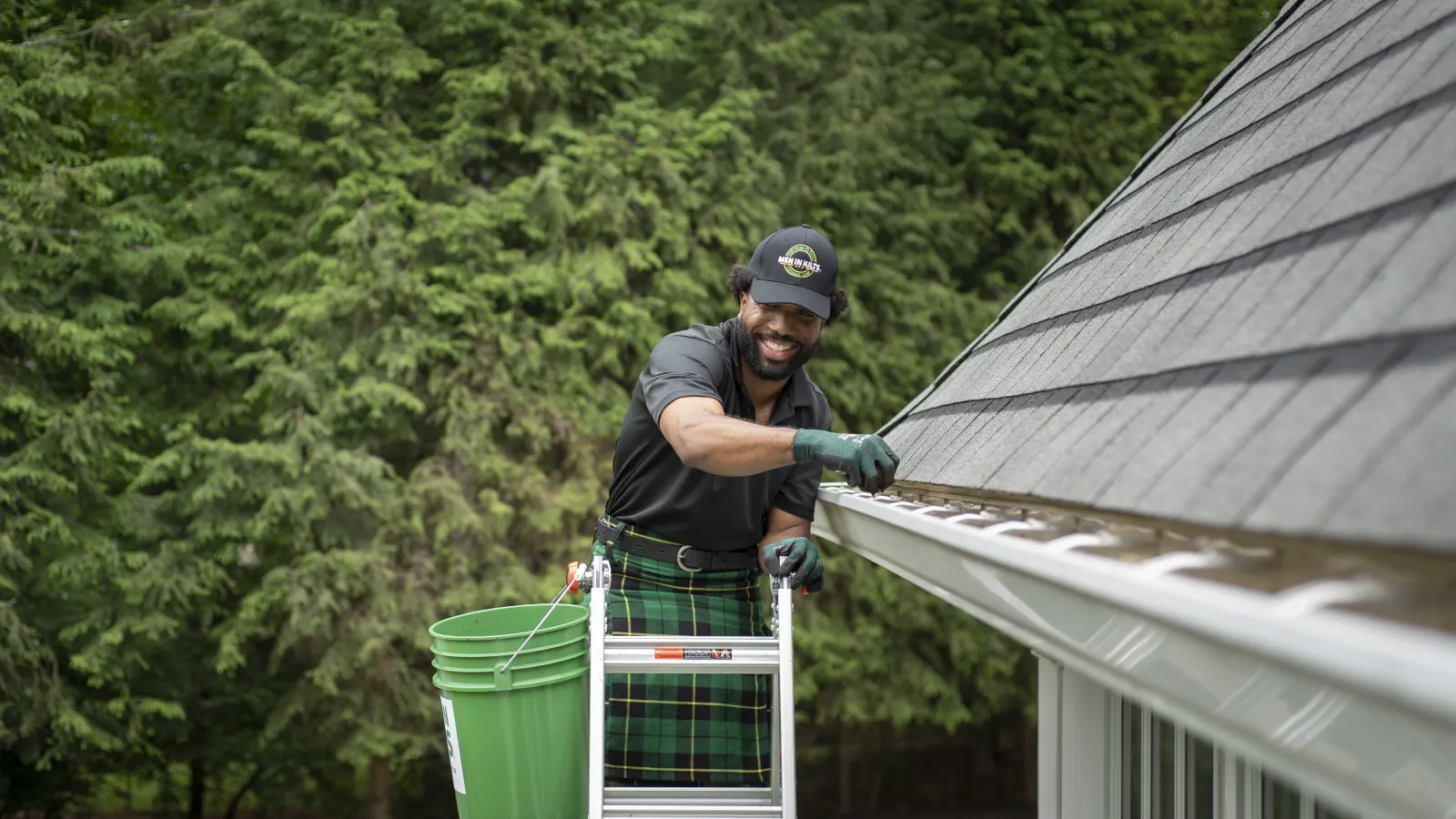 a person holding a green bucket cleaning a gutter