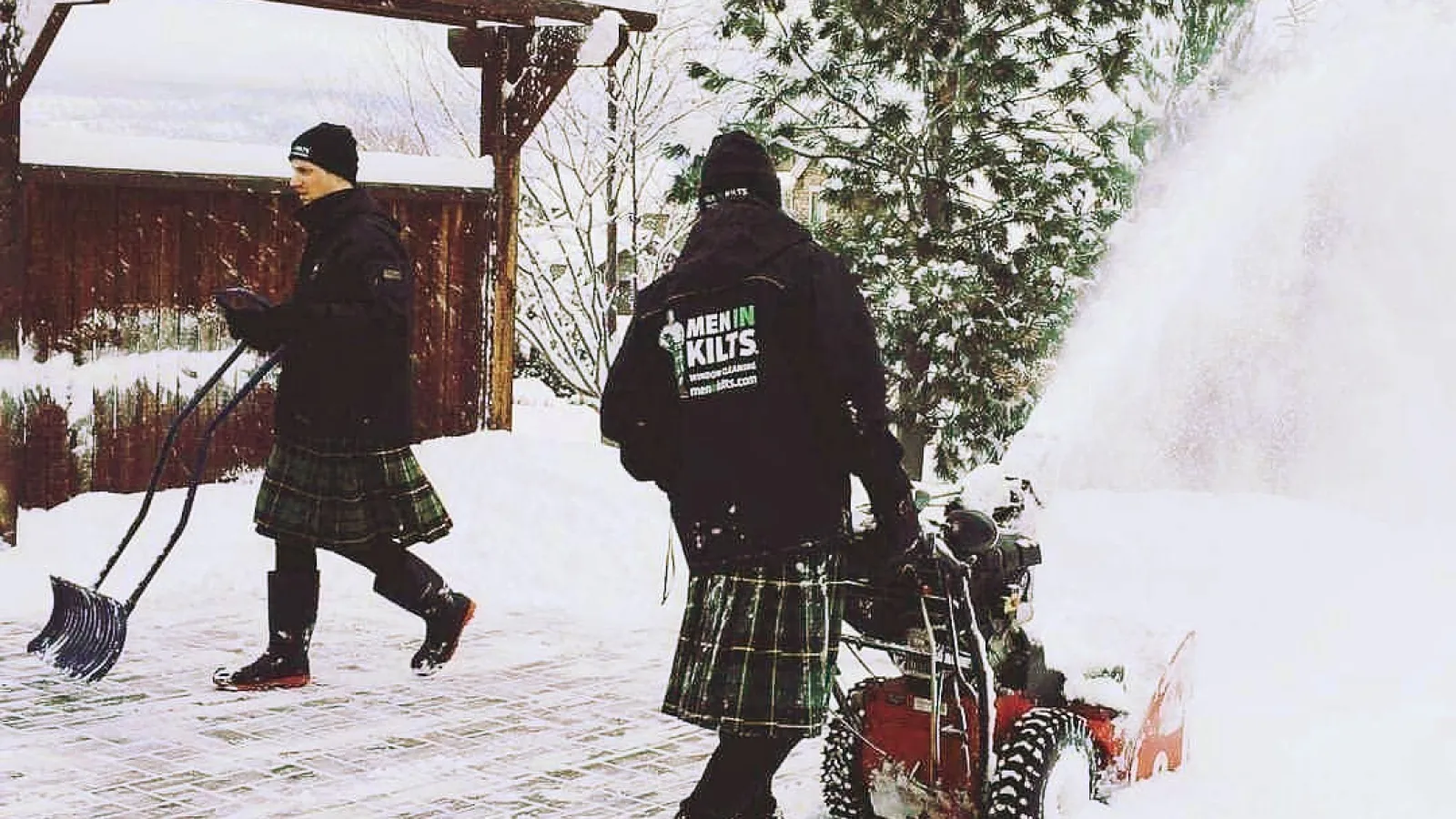 a couple of people snow blowing a driveway