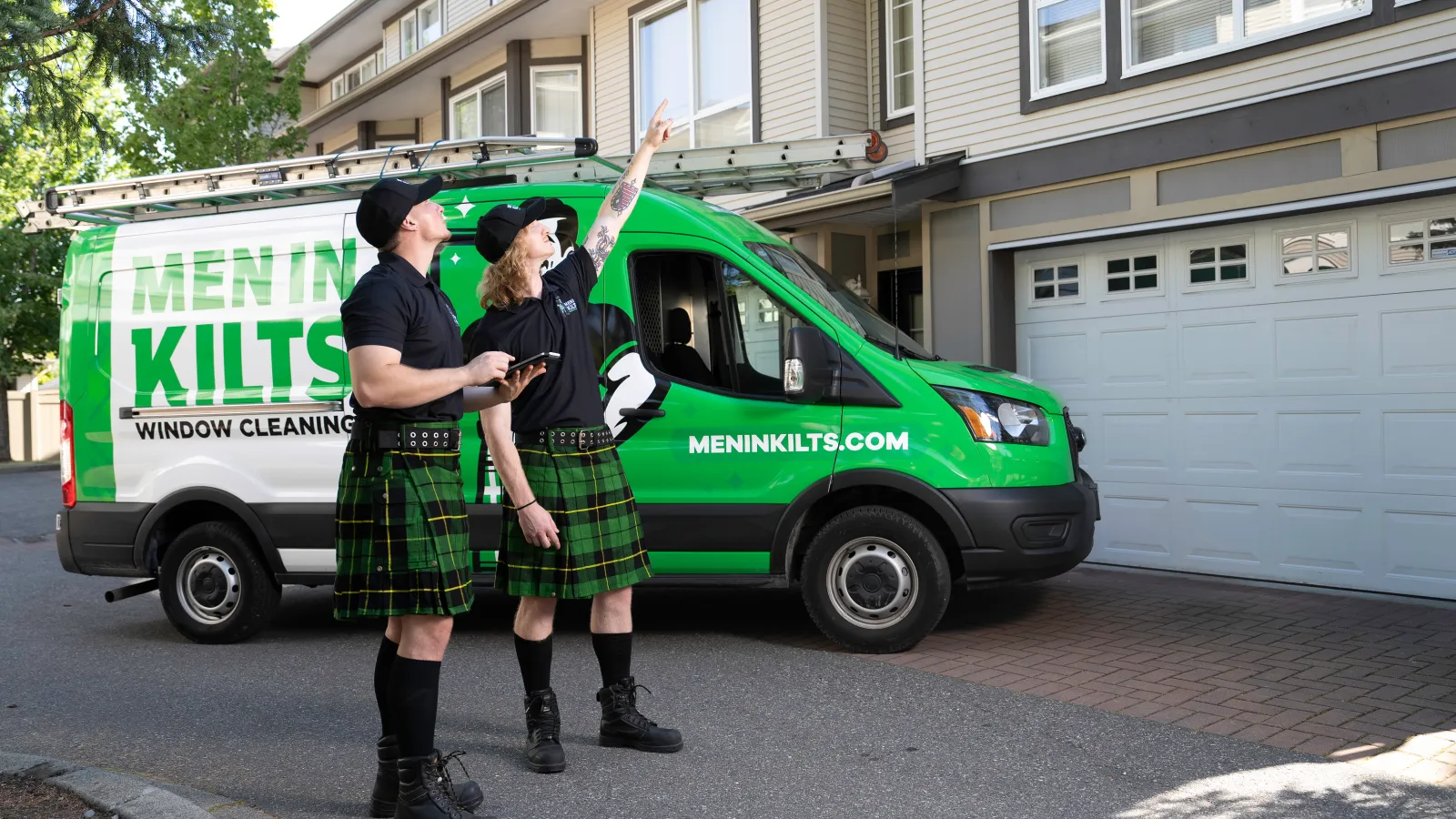 two people in kilts standing in front of a green van